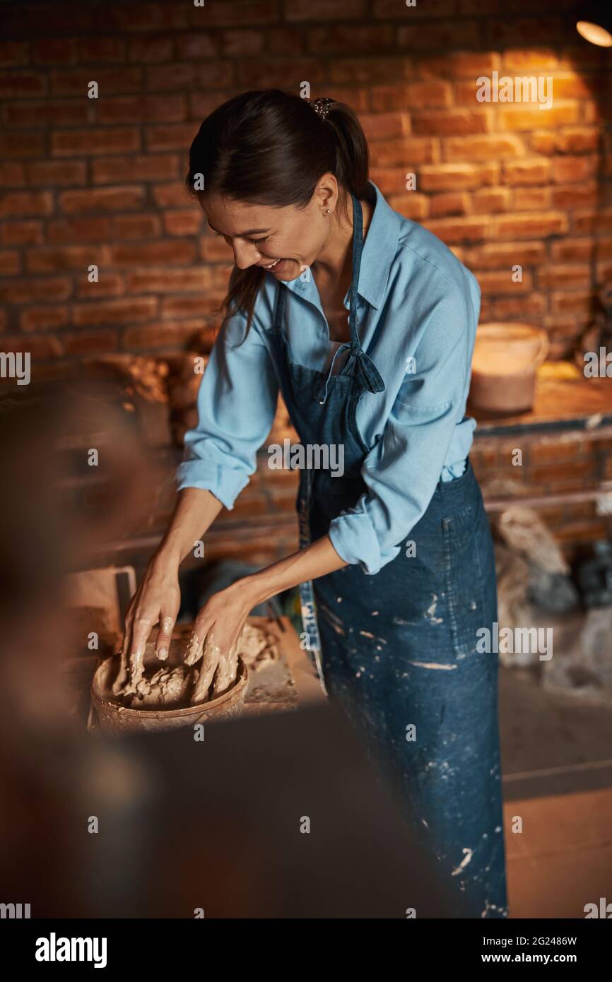 Charmanter junger kaukasischer Keramiker, der frischen, nassen Ton in einem Kunststudio quetscht Stockfoto