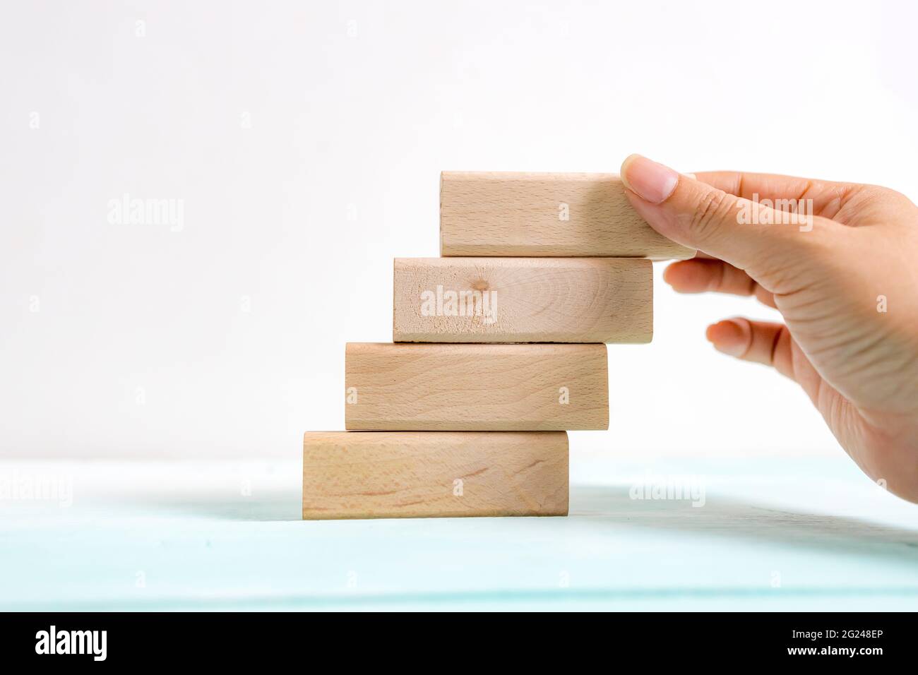 Holzblock, der von Hand als Treppenstufe stapelt, anordnen. Geschäftskonzept für Wachstumserfolg. Stufen Sie als Symbol für die berufliche Weiterentwicklung oder die geschäftlichen s Stockfoto