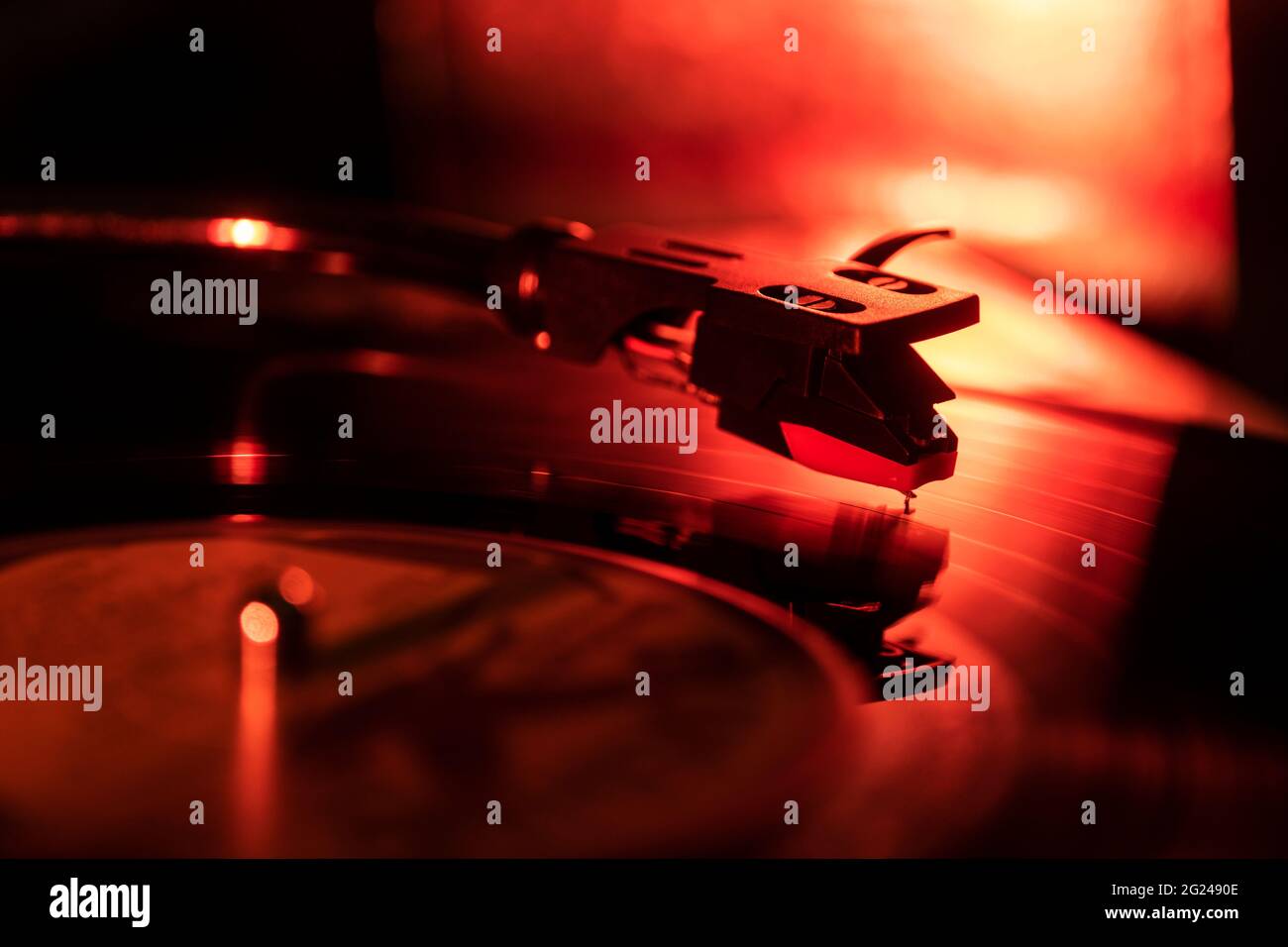 Nahaufnahme einer Nadel eines Plattenspielers auf der Schallplatte in rotem Licht Stockfoto