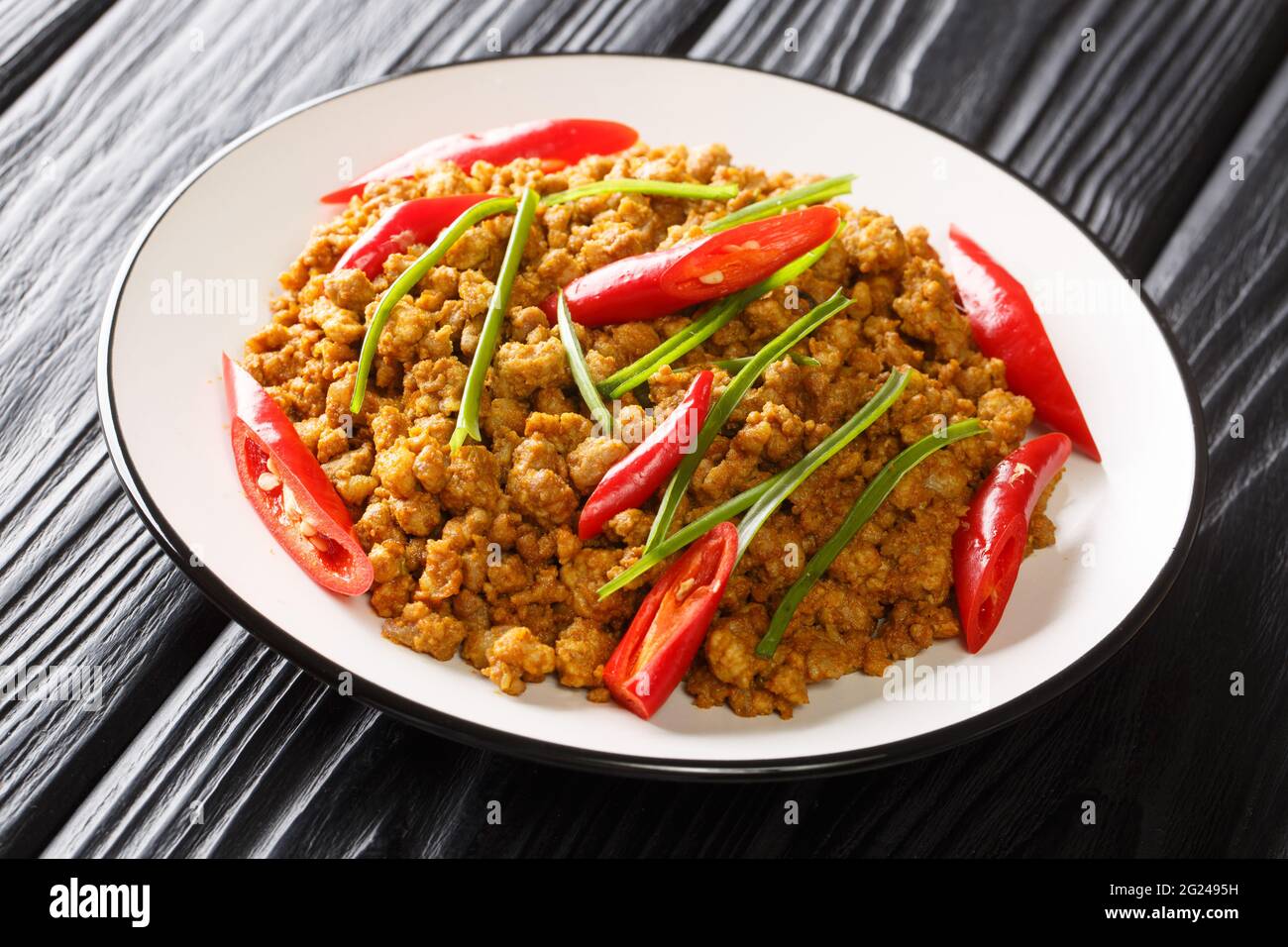 Leckere Khua Kling südthailändische Sorte von trockenem Kurry kombiniert würzige Kurry-Paste und gemahlenes Schweinefleisch aus nächster Nähe auf dem Teller auf dem Tisch. Horizontal Stockfoto
