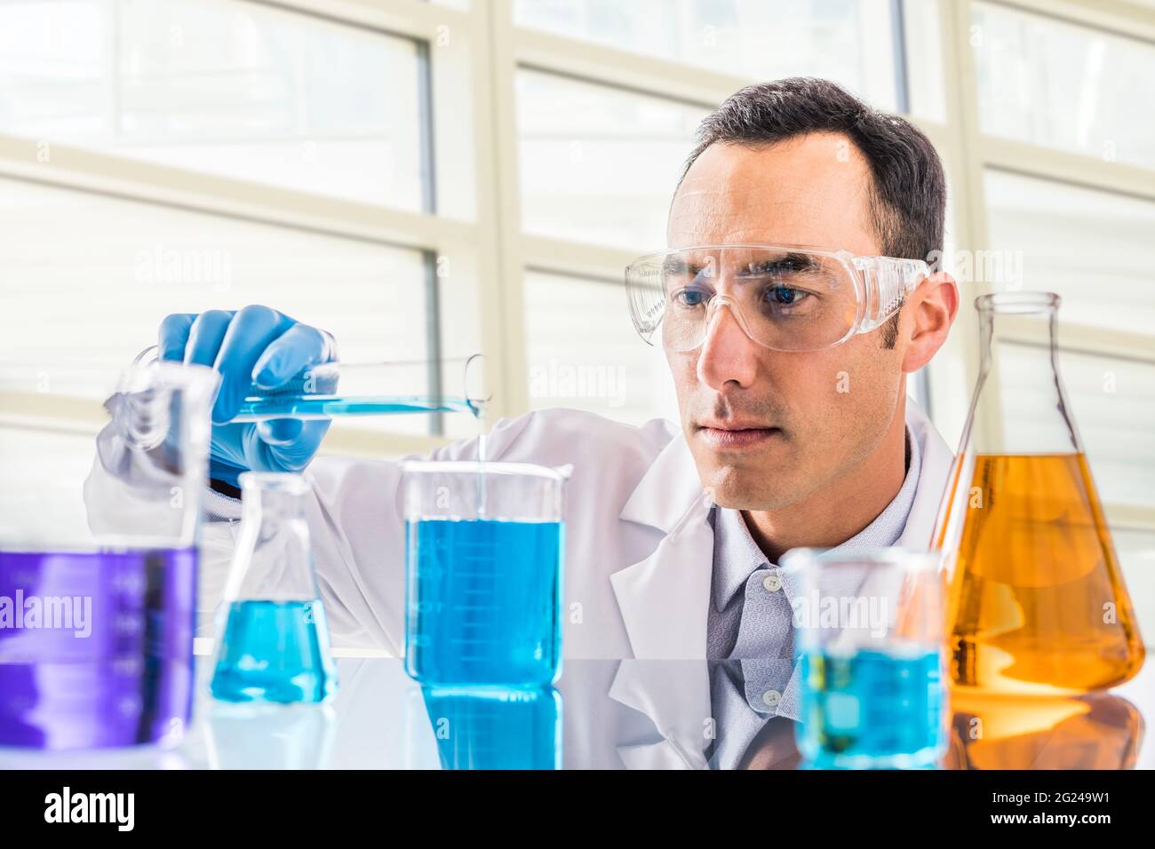 Wissenschaftler gießen blaue Flüssigkeit im Labor Stockfoto