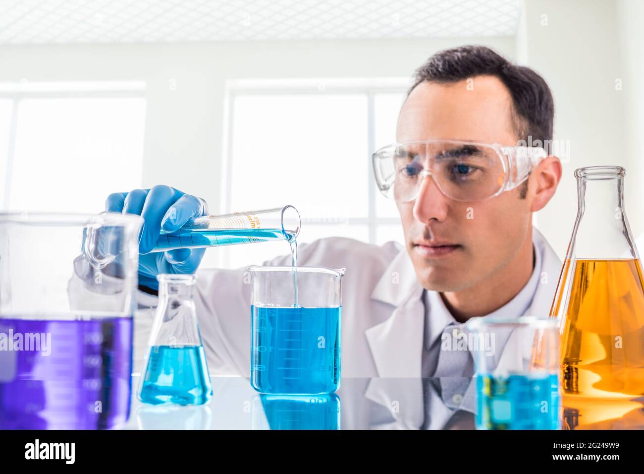 Wissenschaftler gießen blaue Flüssigkeit im Labor Stockfoto