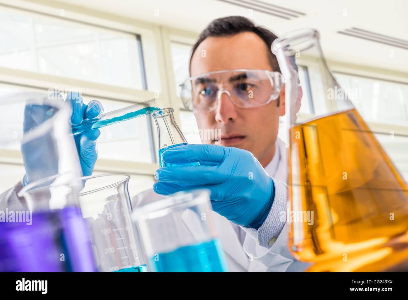 Wissenschaftler gießen blaue Flüssigkeit im Labor Stockfoto