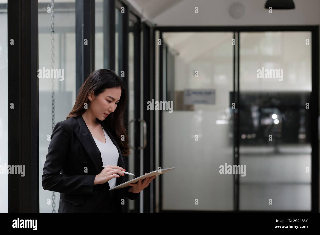 Asiatische Geschäftsfrau hält Stylus Pen Schreiben auf digitalen Tablet am Besprechungstisch Stockfoto