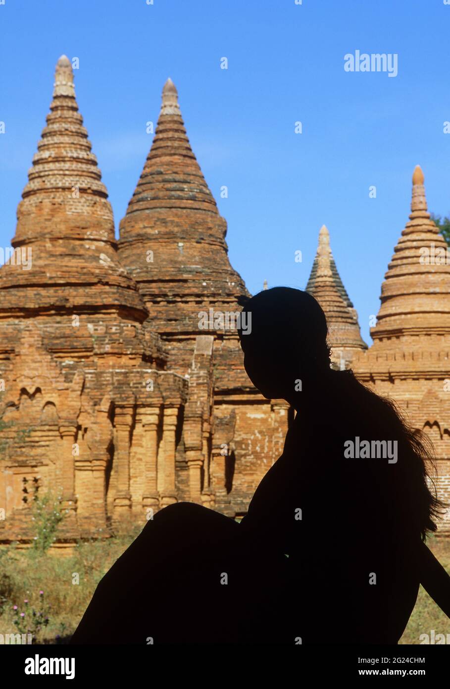 Myanmar, Bagan, Mandalay Division, Silhouette einer jungen Frau, die vor buddhistischen Pagoden sitzt Stockfoto