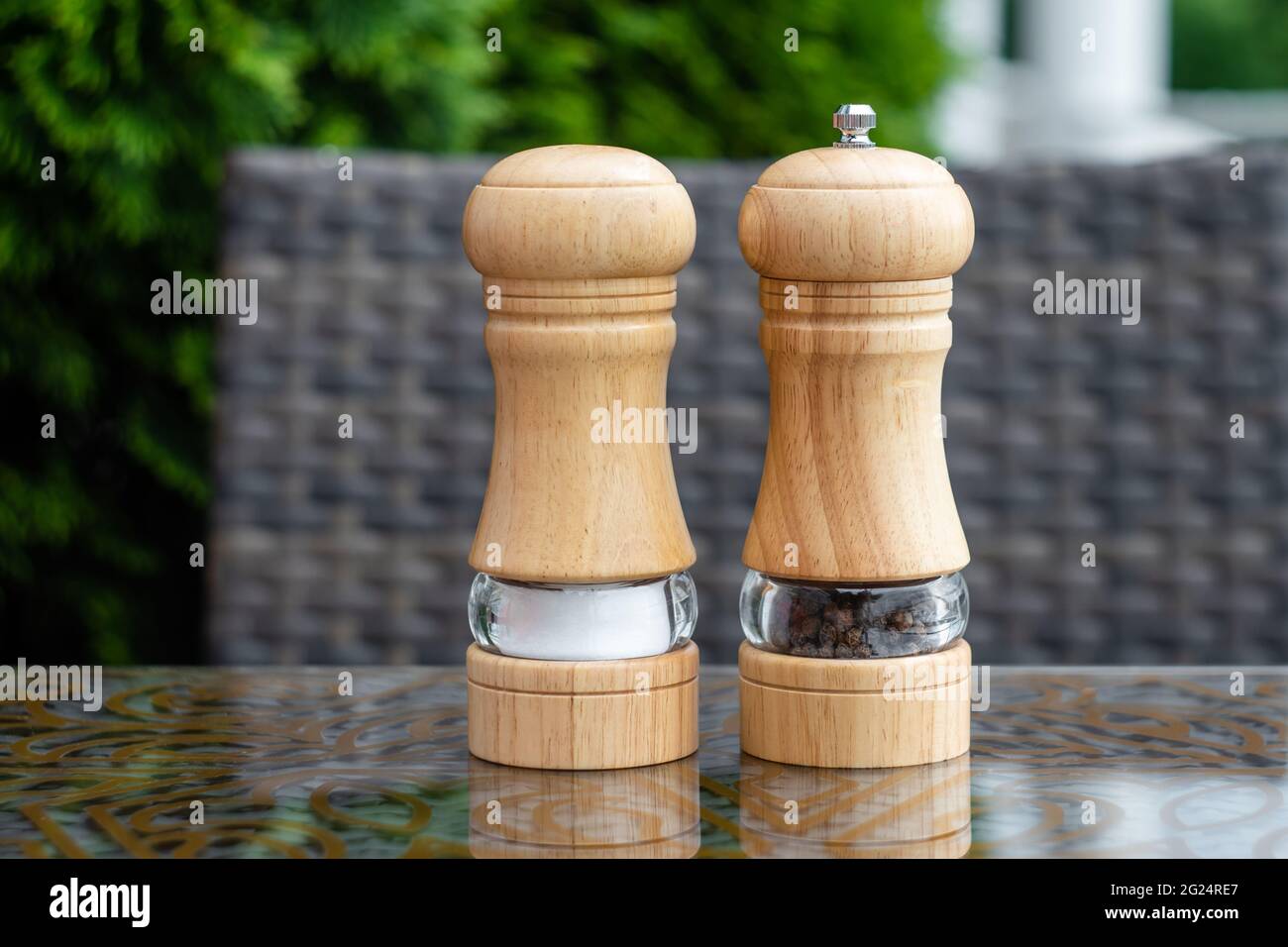 Salz- und Schwarzpfeffer-Shaker in einem Sommercafé, eine hölzerne Pfeffermühle auf einem Tisch in einem Restaurant. Gewürze, Zutaten beim Kochen Stockfoto