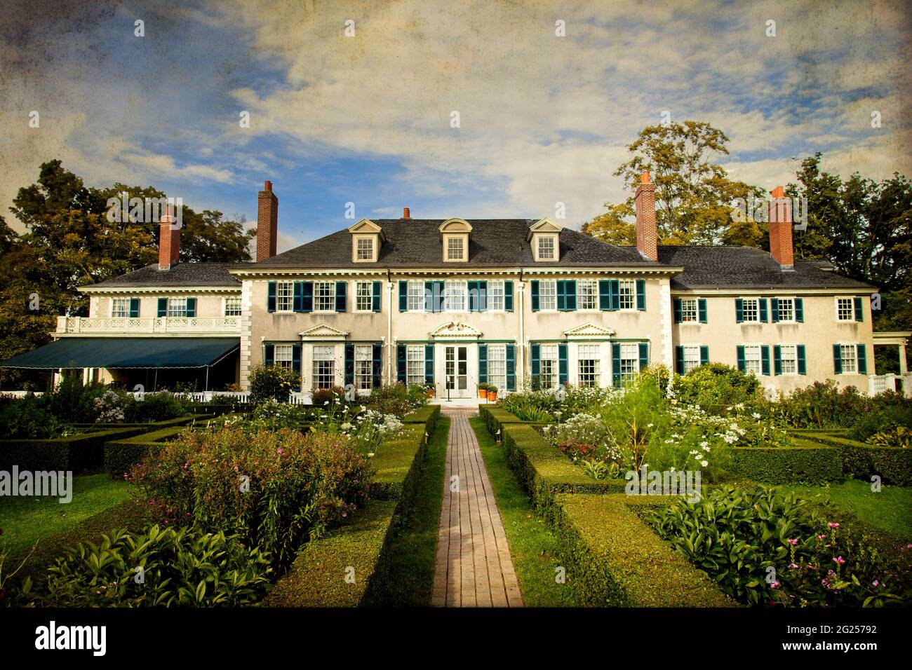 Strukturiertes und stilisiertes Foto von Robert Lincolns Sommerhaus in Manchester, Vermont; formelle Gärten, Dachgauben, Fensterläden, Hecken, wolkig. Stockfoto
