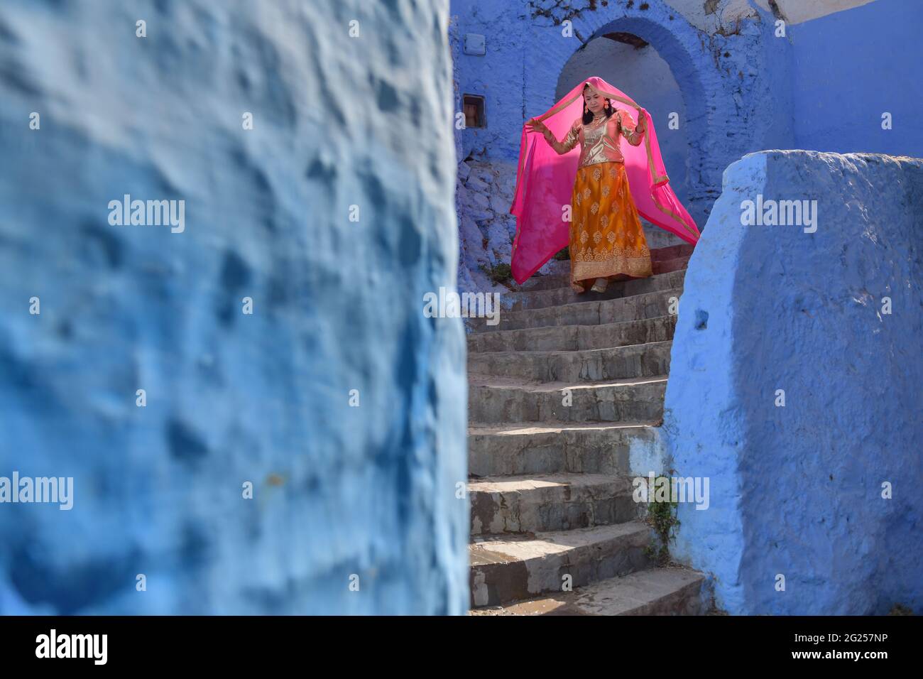 Frau in traditioneller Kleidung, die die Treppe hinunter geht, Chefchaouen, Marokko Stockfoto