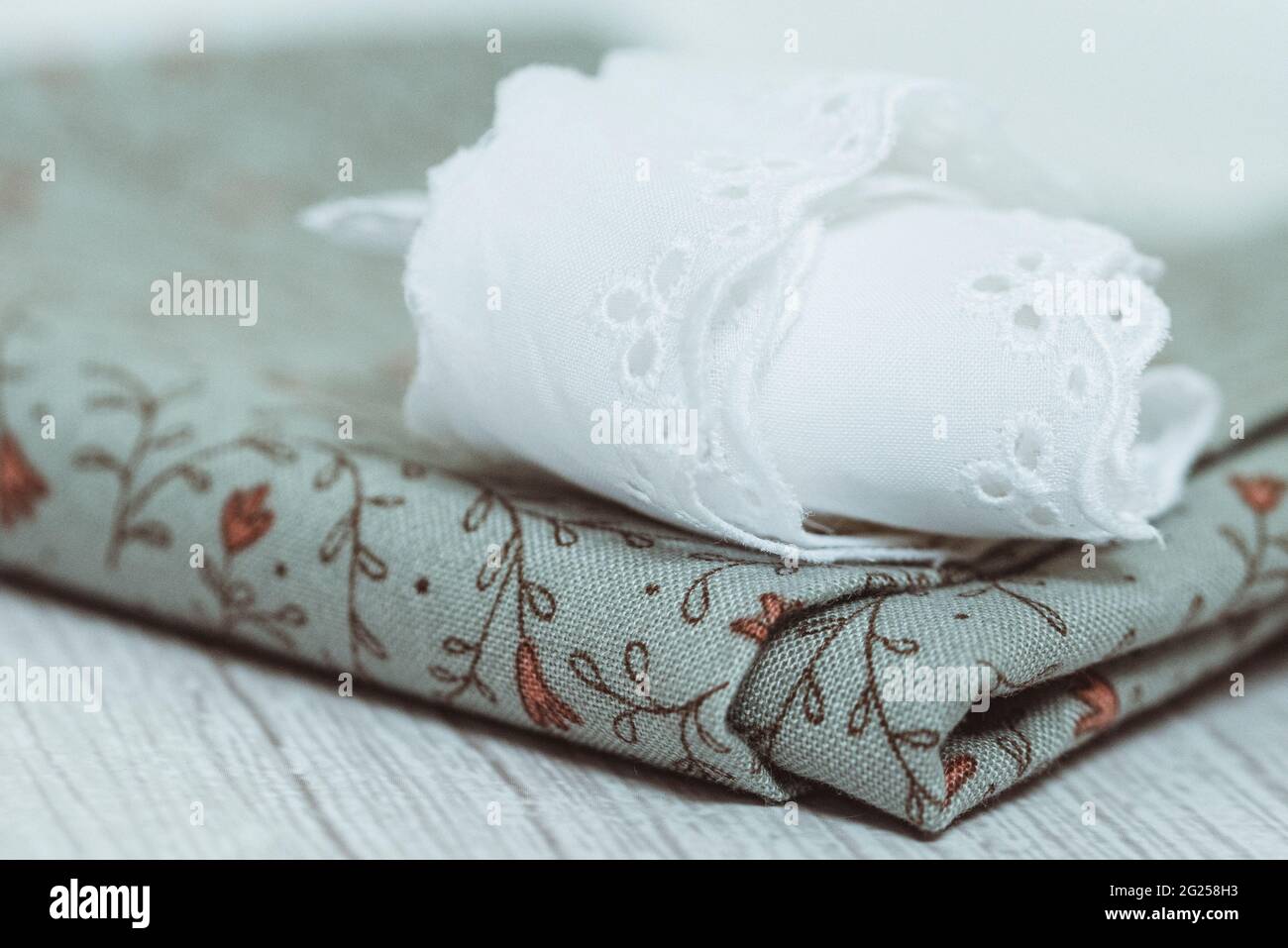 Serviette aus Spitze, gefaltet auf einem floralen Stück Stoff Stockfoto
