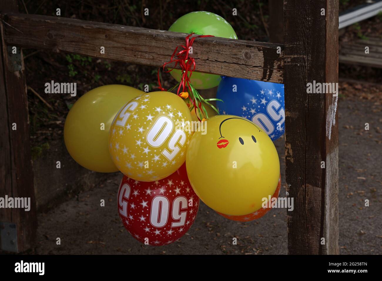 Gruppe von hellen, bunten Ballons zum 50. Geburtstag, die an einen Holzbalken gebunden sind Stockfoto