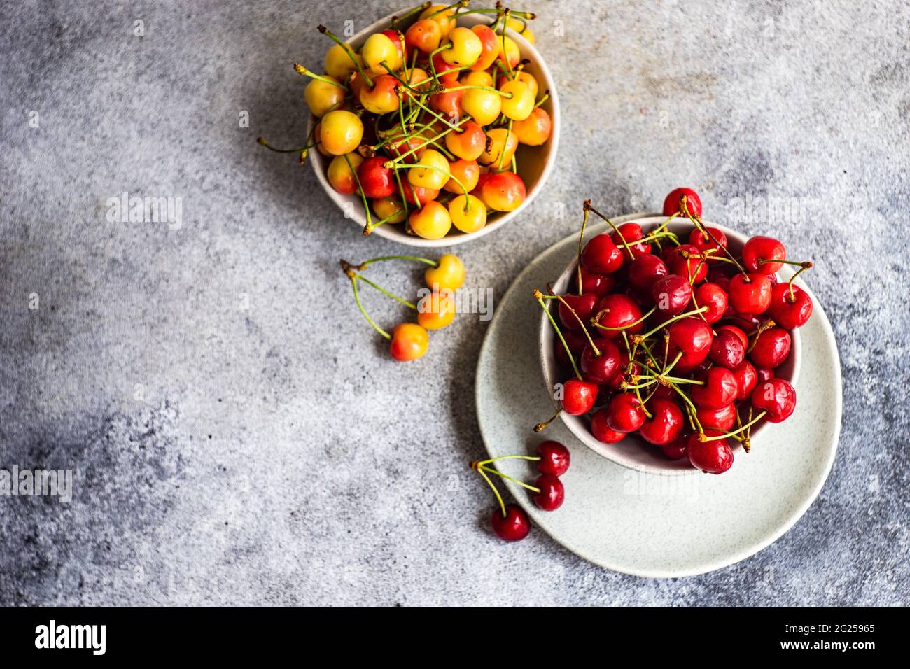 Blick von oben auf Schalen mit roten und gelben Kirschen Stockfoto