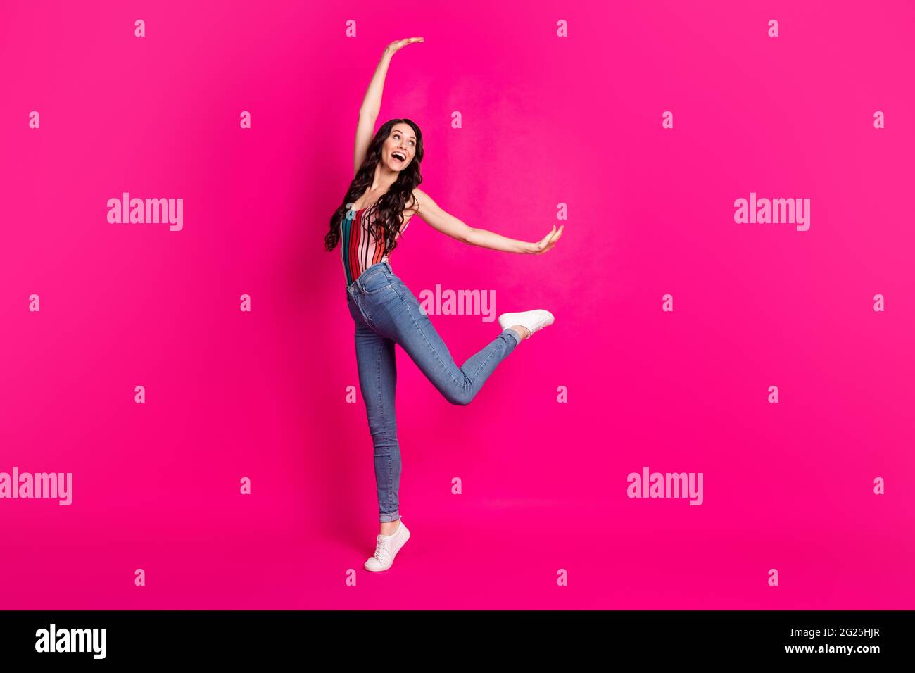 Full size Profil Foto von optimistischen niedlichen Brünette Dame Tanz tragen Top Jeans Sneakers isoliert auf lebendige rosa Farbe Hintergrund Stockfoto