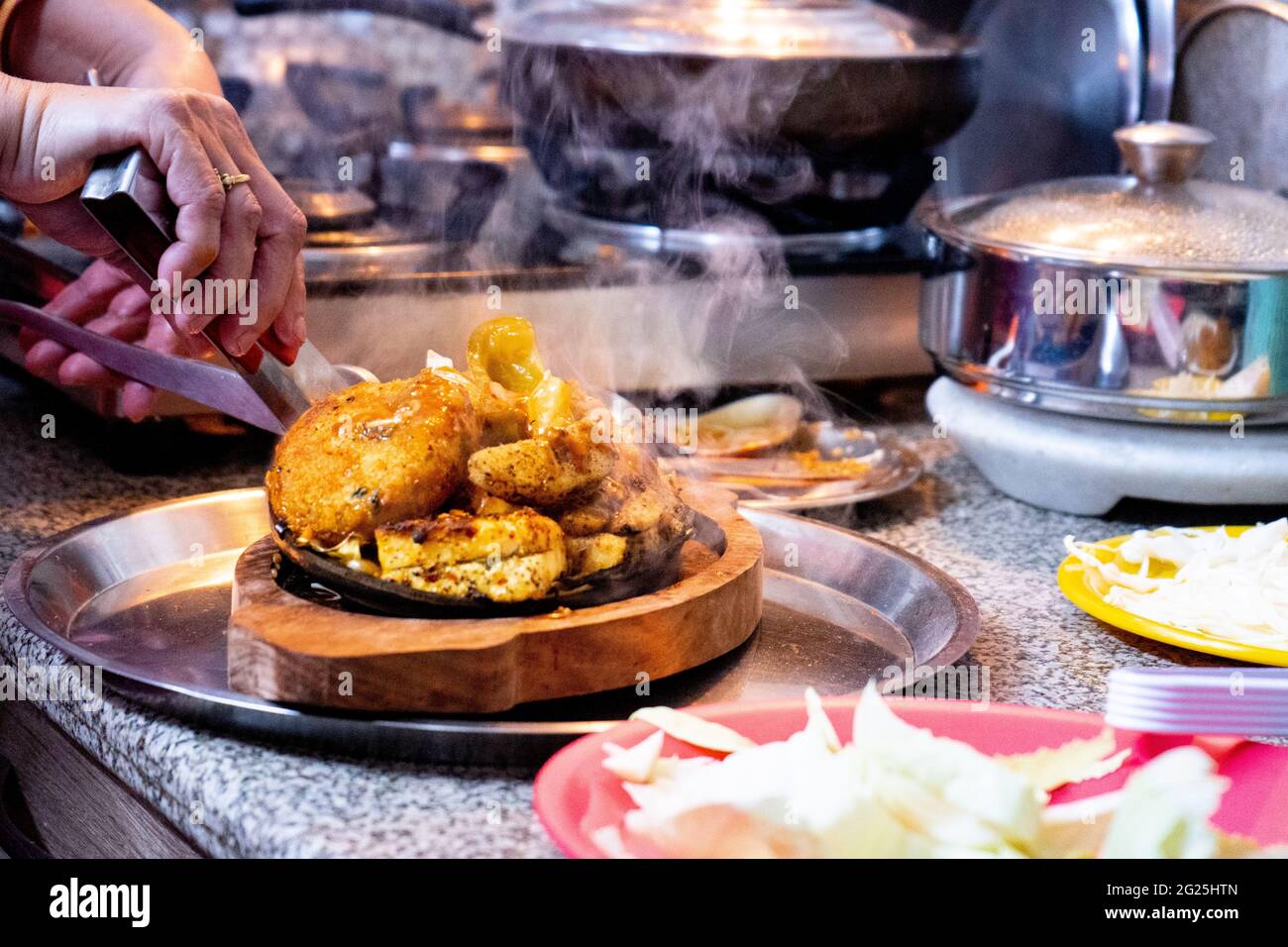 Indische asiatische sizzler Gericht auf einem Holztablett mit einer  eisernen Kochplatte serviert, die das Gemüse wie Kohlkartoffelreis  verursacht zu kochen und zu geben Stockfotografie - Alamy
