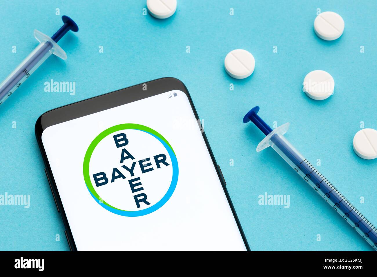 Galicia, Spanien; 8. Juni 2020 : Smartphone mit Bayer-Logo auf dem Bildschirm und Pillen und Spritze auf blauem Hintergrund Stockfoto