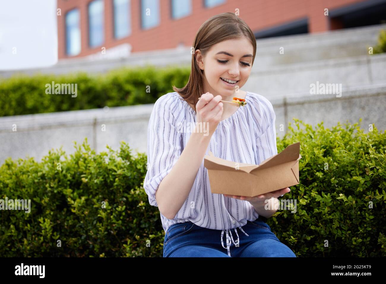 Frau, Die Gesund Vegan Oder Vegetarisch Isst Take Away Lunch Aus Recycelbarer Verpackung Mit Holzgabel Stockfoto