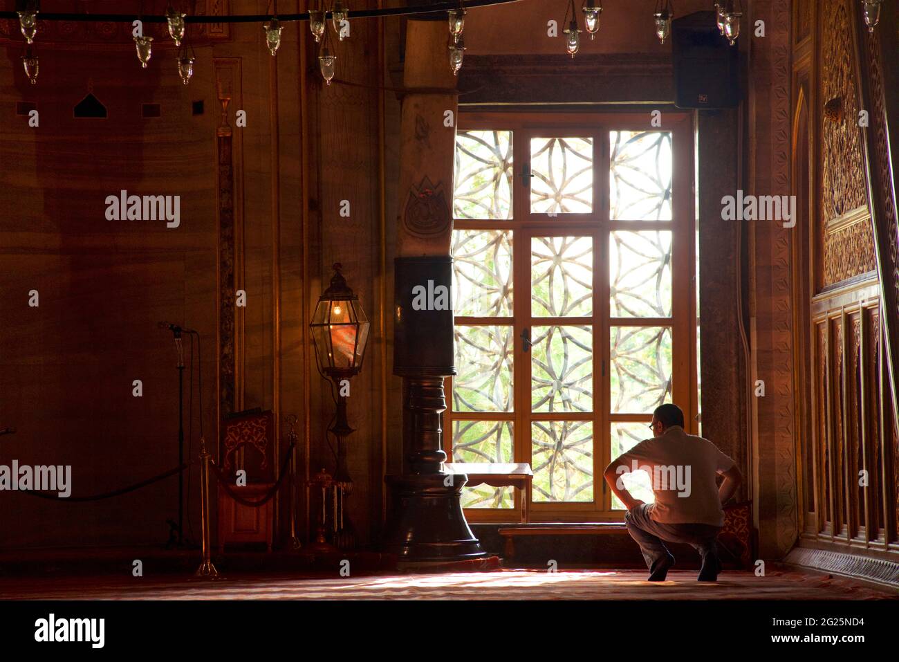 Das Innere der Sultan Ahmed Moschee (türkisch: Sultan Ahmet Camii), auch als Blaue Moschee bekannt. Eine Freitagsmoschee aus osmanischer Zeit in Istanbul, Türkei. Mann am Fenster in Silhouette. Stockfoto