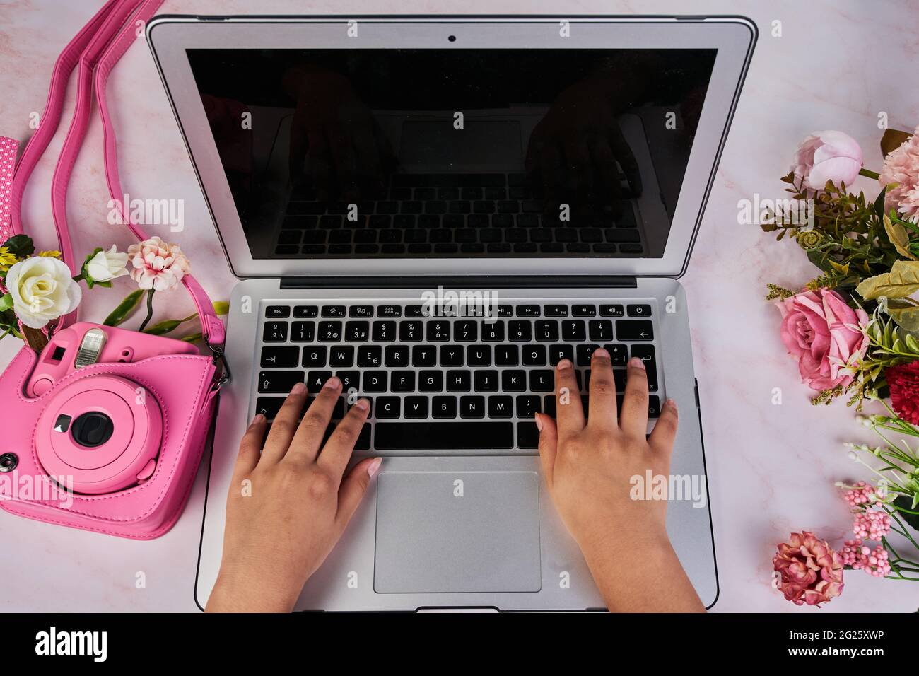 Hände auf einen Computer mit Blumen und eine Fotokamera feminines Konzept Stockfoto