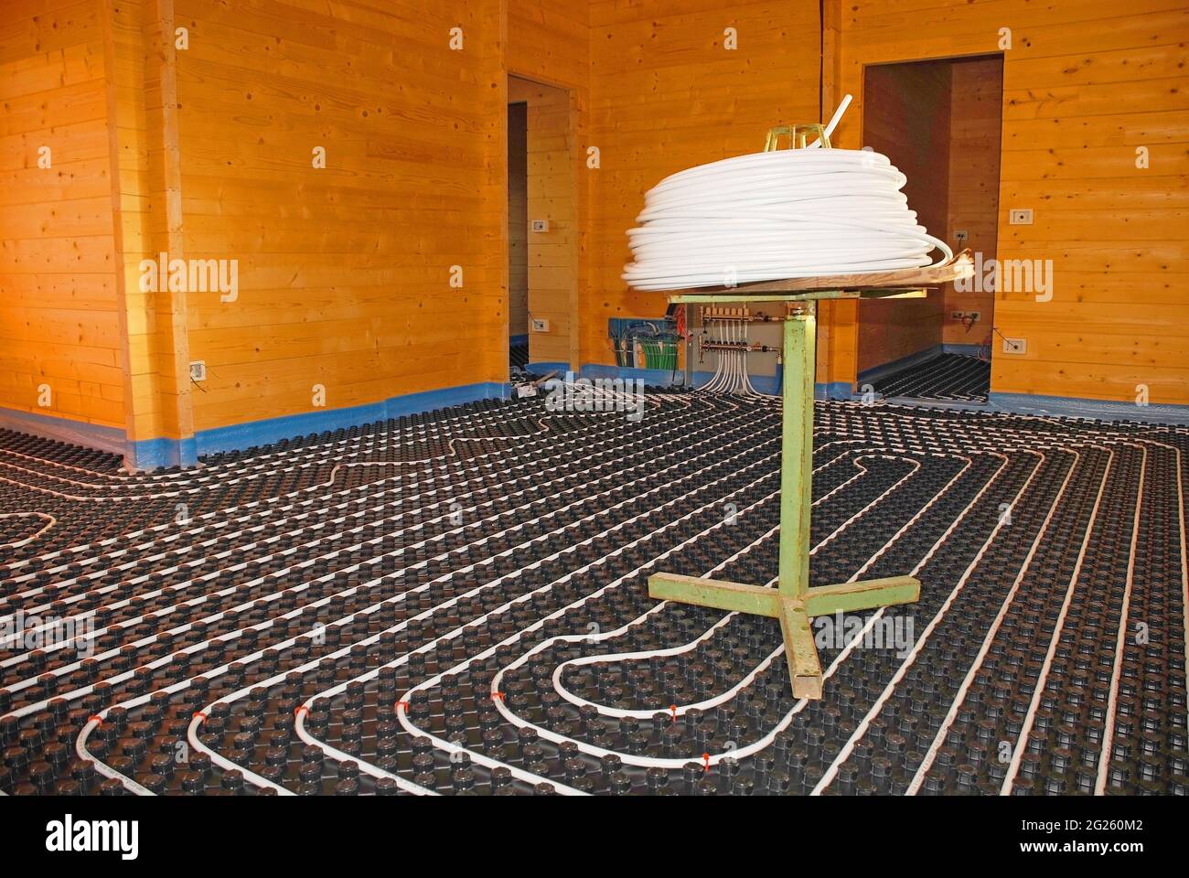 Hydroonisches Fußbodenheizungssystem mit geschlossenem Regelkreis auf gegossenem Isolierpaneel aus EPS mit Spultisch in einem teilweise gebauten Holzhaus Stockfoto
