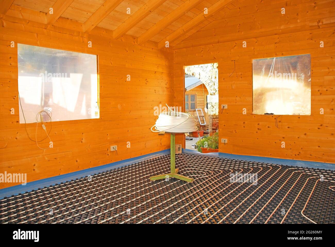 Hydroonisches Fußbodenheizungssystem mit geschlossenem Regelkreis auf gegossenem Isolierpaneel aus EPS mit Spultisch in einem teilweise gebauten Holzhaus Stockfoto