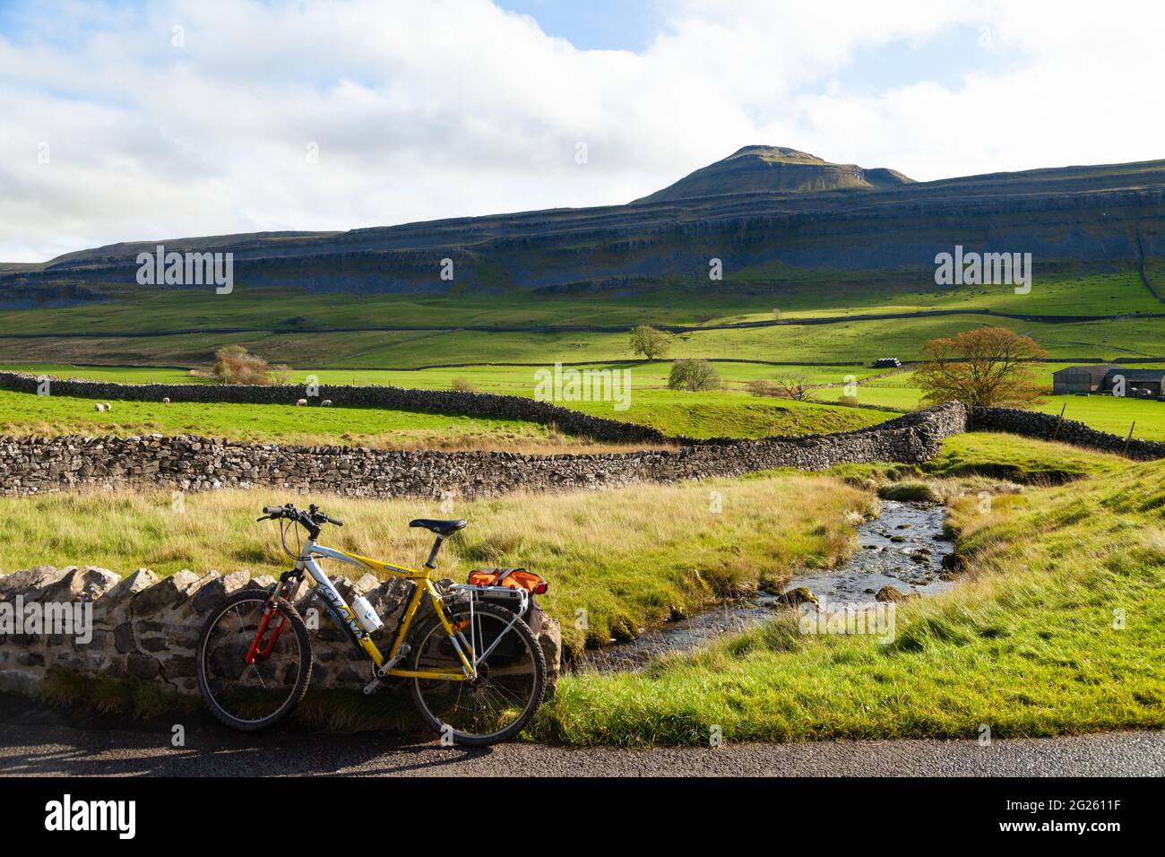 Ein Mountainbike gegen eine Mauer entlang der B 6255 mit Ingleborough Hügel im Hintergrund ruhen, Yorkshire Dales, England. Stockfoto