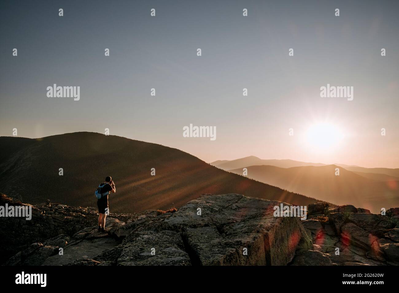 Männlicher Wanderer fotografiert den Sonnenaufgang über den White Mountains in New Hampshire Stockfoto