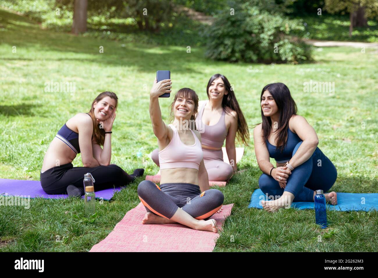 Eine Gruppe junger kaukasischer Frauen, die während eines Yoga-Kurses im Freien ein Foto machen. Platz für Text. Stockfoto