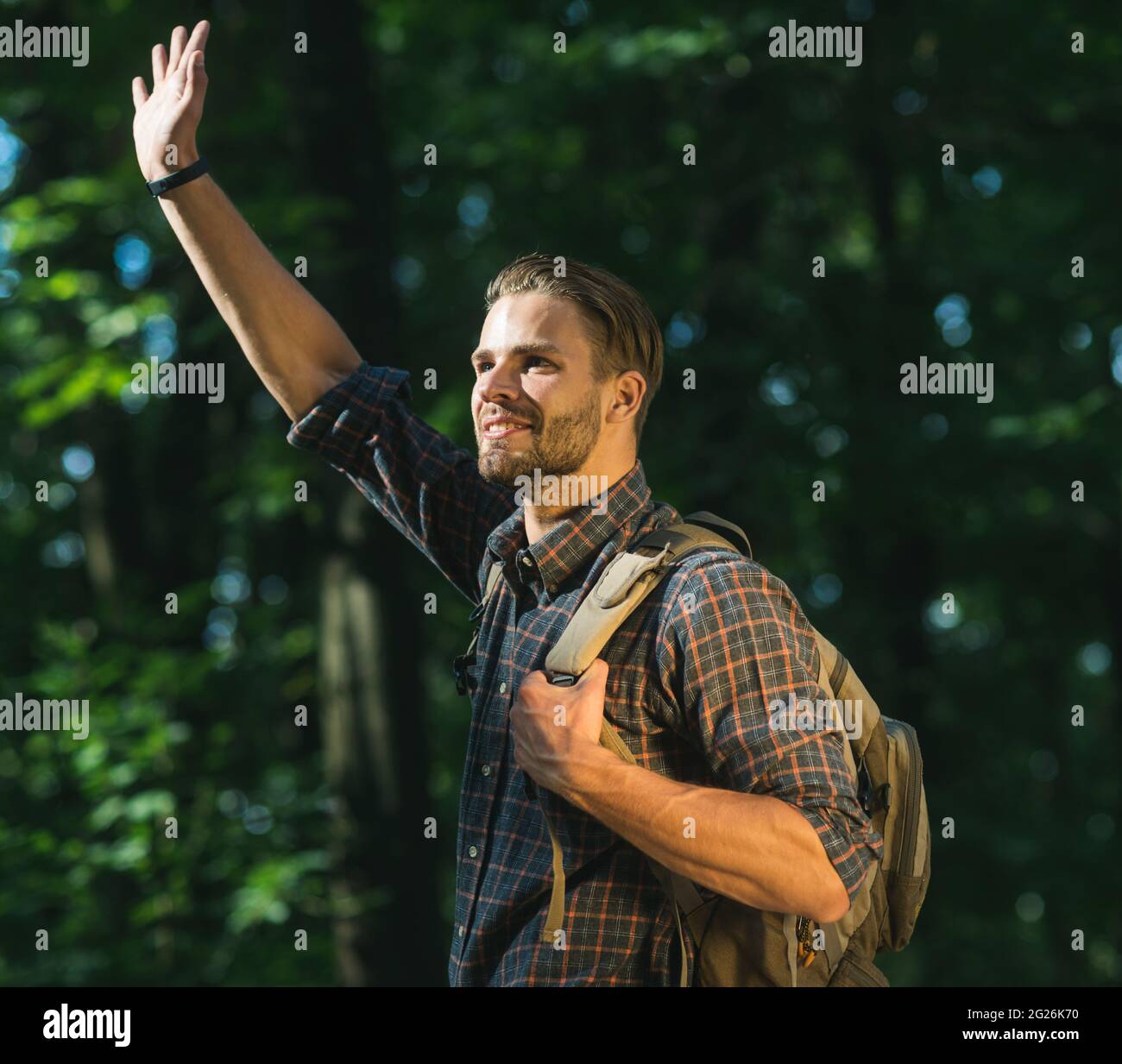 Glücklicher Reisender mit Rucksack in Wäldern. Reisen, Tourismus, Wandern, Erlebniskonzept. Stockfoto