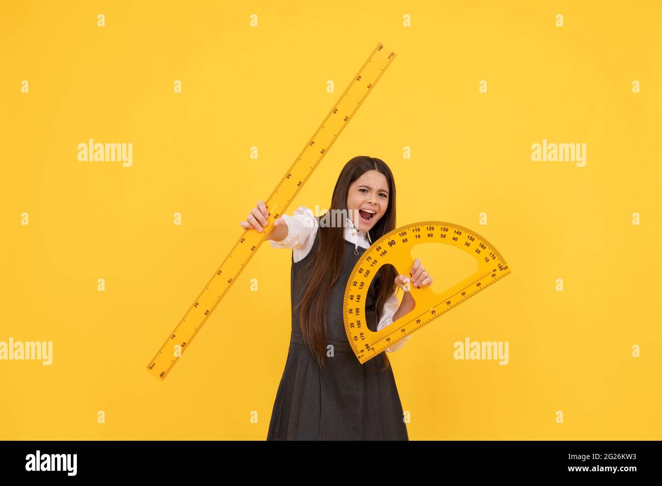 Emotional Kind halten Mathematik Winkelmesser und Lineal in der Schule auf gelbem Hintergrund, Bildung Stockfoto