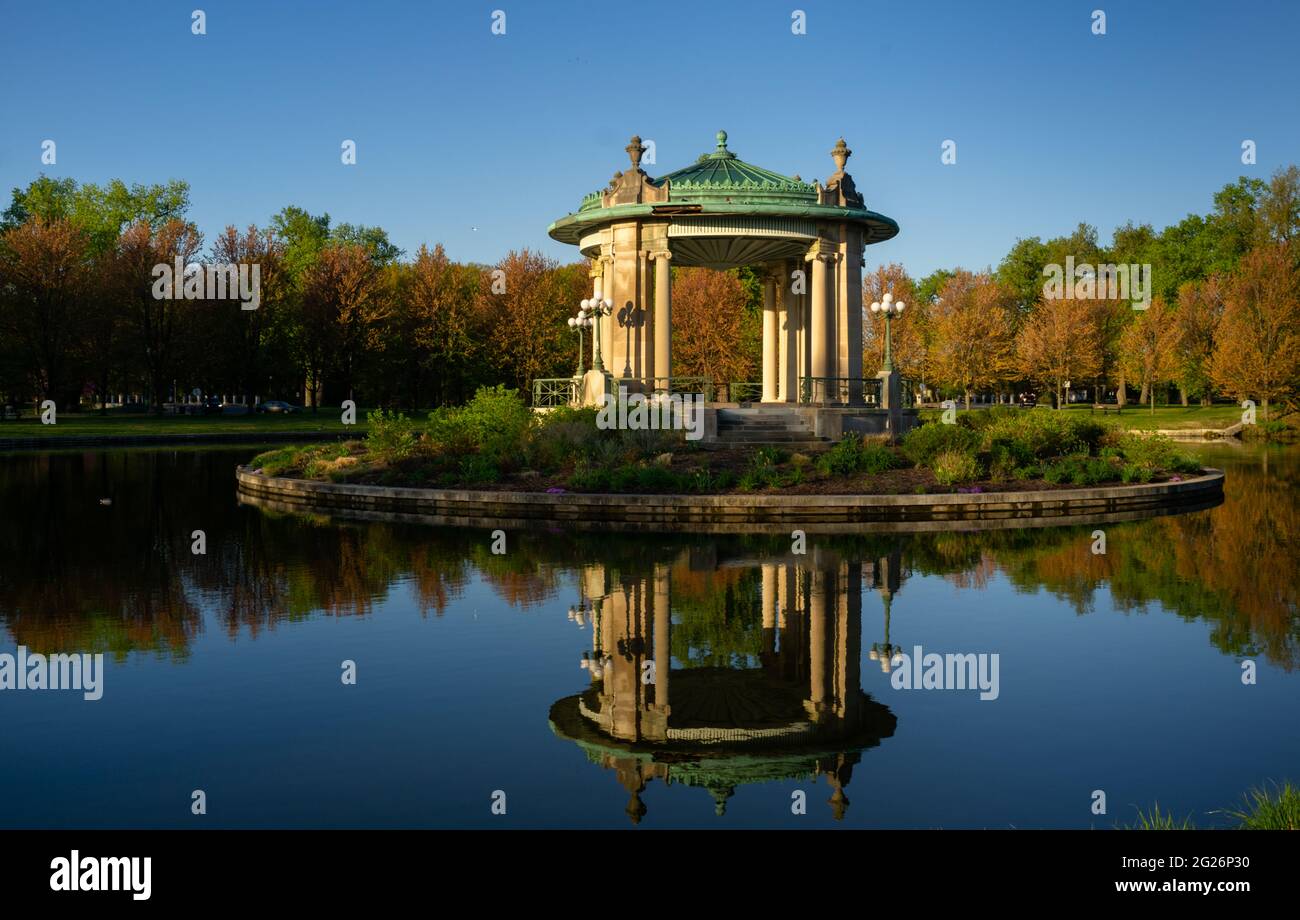 19. April 2021 - ST. LOUIS - Sonnenaufgang beleuchtet den Nathan Frank Bandstand am Pagoda Lake im Forest Park, dem 1,326 Hektar großen Stadtpark in St. Loui Stockfoto
