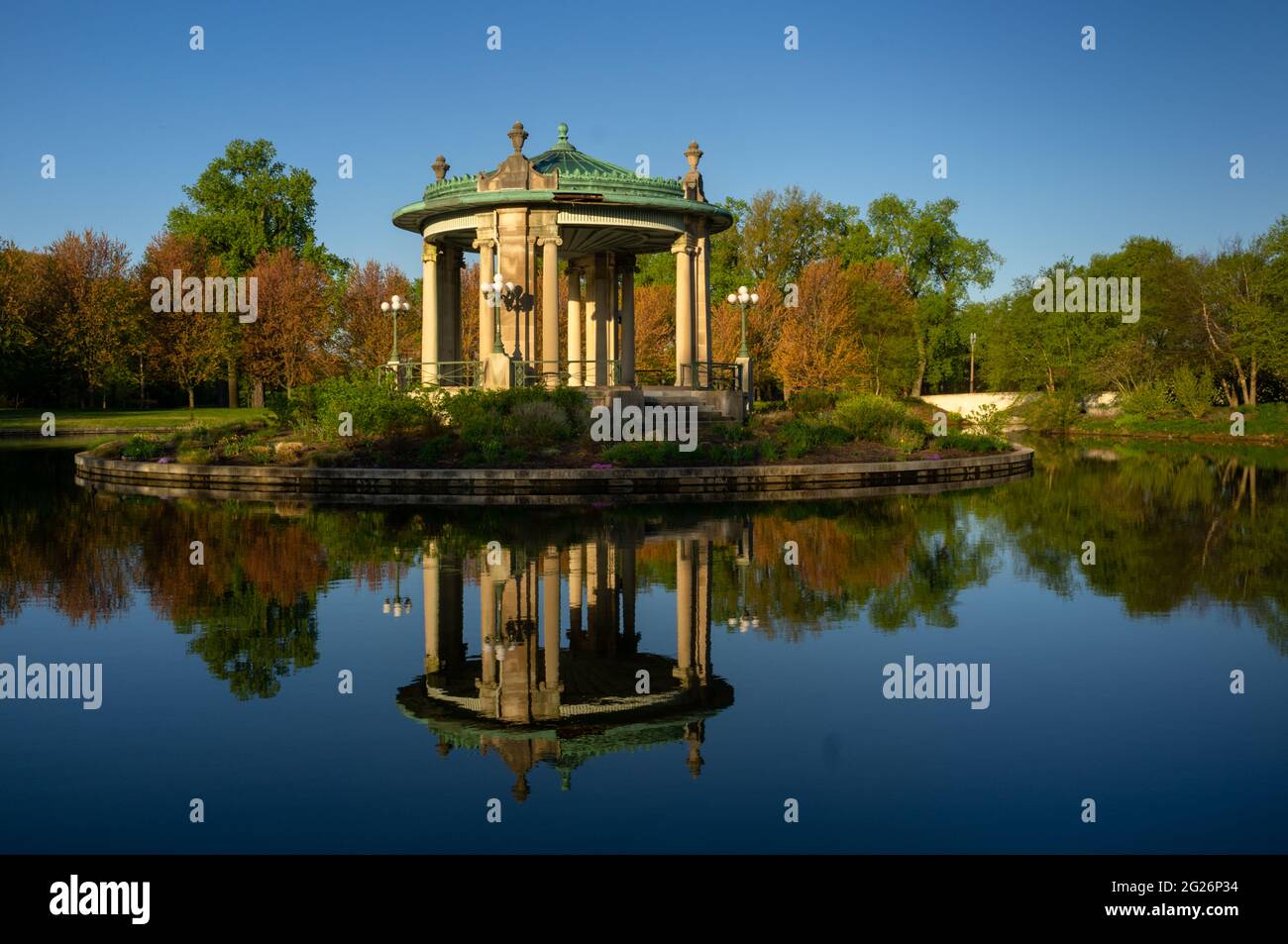 19. April 2021 - ST. LOUIS - Sonnenaufgang beleuchtet den Nathan Frank Bandstand am Pagoda Lake im Forest Park, dem 1,326 Hektar großen Stadtpark in St. Loui Stockfoto