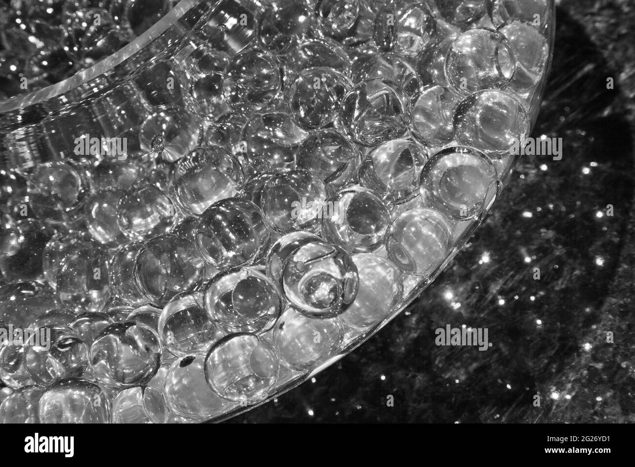 Abstraktes Bild von durchsichtigen Glaskugeln in einer Glasschale, die auf einem Spiegel sitzt Stockfoto