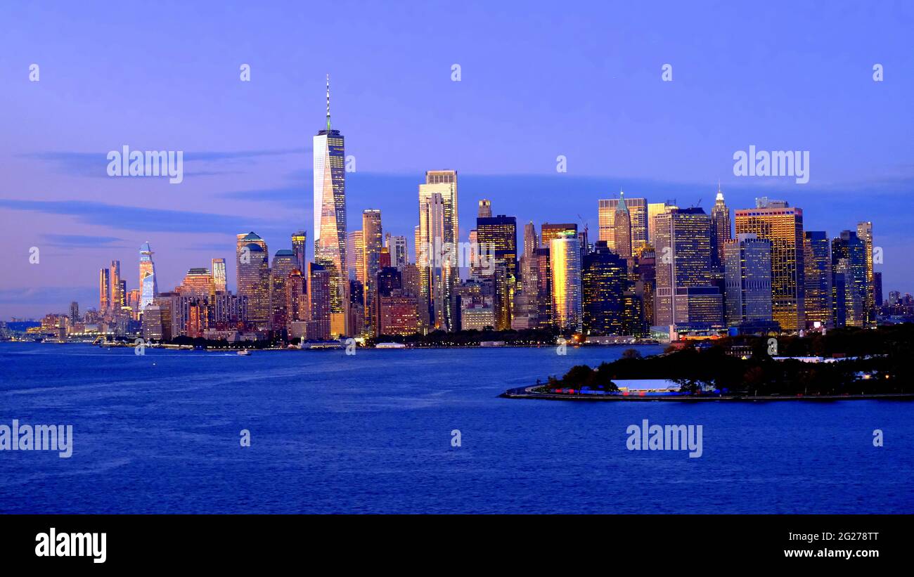 USA; NEW YORK CITY; SKYLINE VON LOWER MANHATTAN IN DER ABENDDÄMMERUNG; FREEDOM TOWER; GOVERNOR'S ISLAND IM VORDERGRUND Stockfoto
