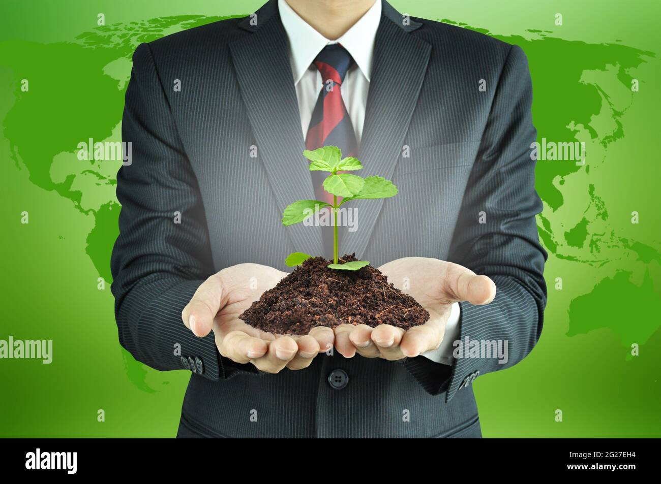 Geschäftsmann hält grünen Keimling mit Boden - nachhaltiges Entwicklungs- & Naturschutzkonzept Stockfoto