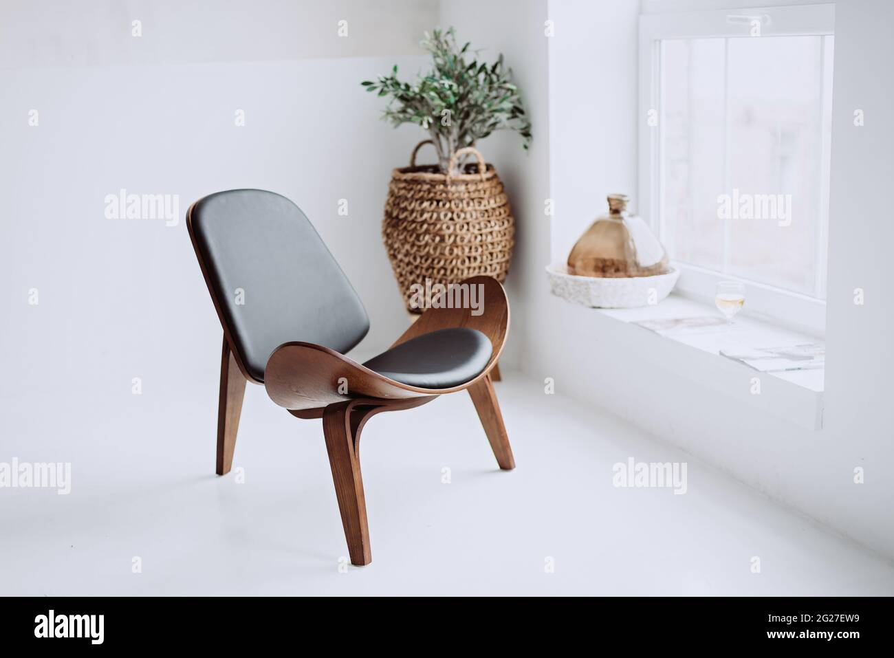 Moderner Sessel aus schwarzem Leder und Holz in einem weißen  Loft-Interieur. Designer-Stuhl. Weicher, selektiver Fokus Stockfotografie -  Alamy