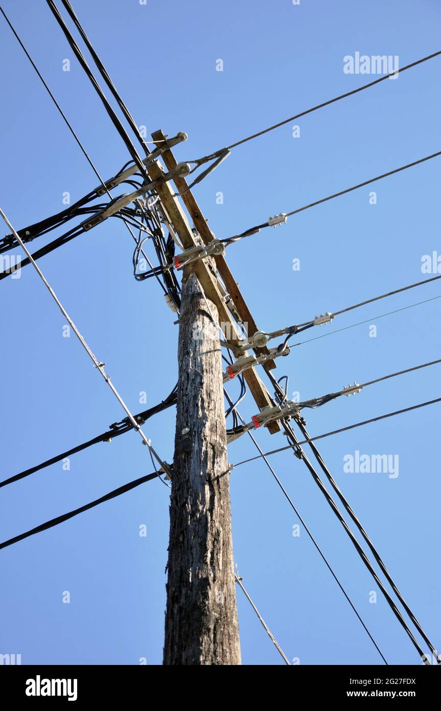 Alte hölzerne Strompfosten mit elektrischen Drähten Stockfoto