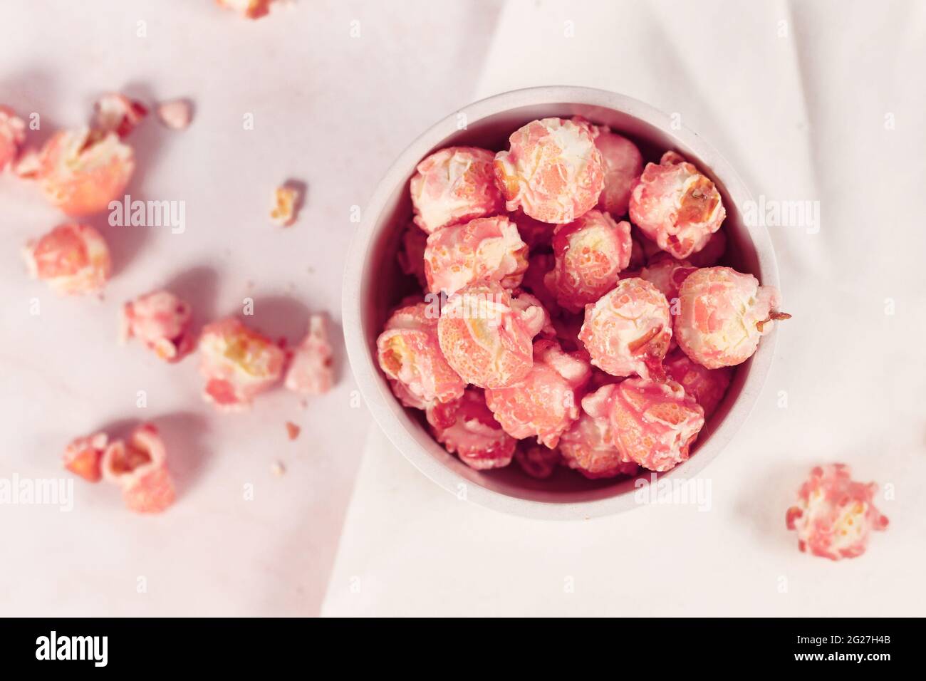 Draufsicht auf rosafarbenes süßes Popcorn mit Erdbeergeschmack in einer weißen Schüssel Stockfoto