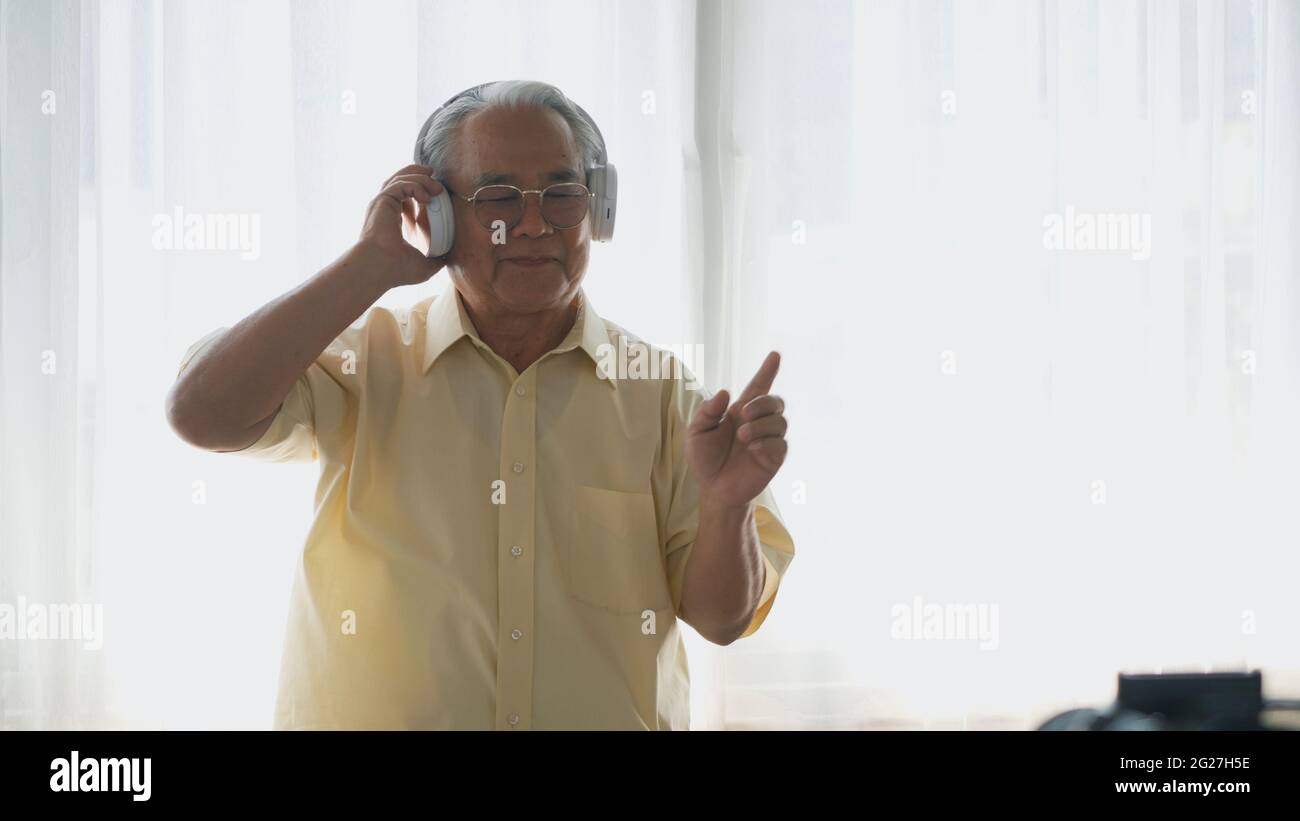 Asiatischer älterer Mann oder Opa, glücklicher älterer Rentner mit Kopfhörern Musik Radio hören und bewegenden Tanz genießen jeden Moment seiner lustigen lif Stockfoto