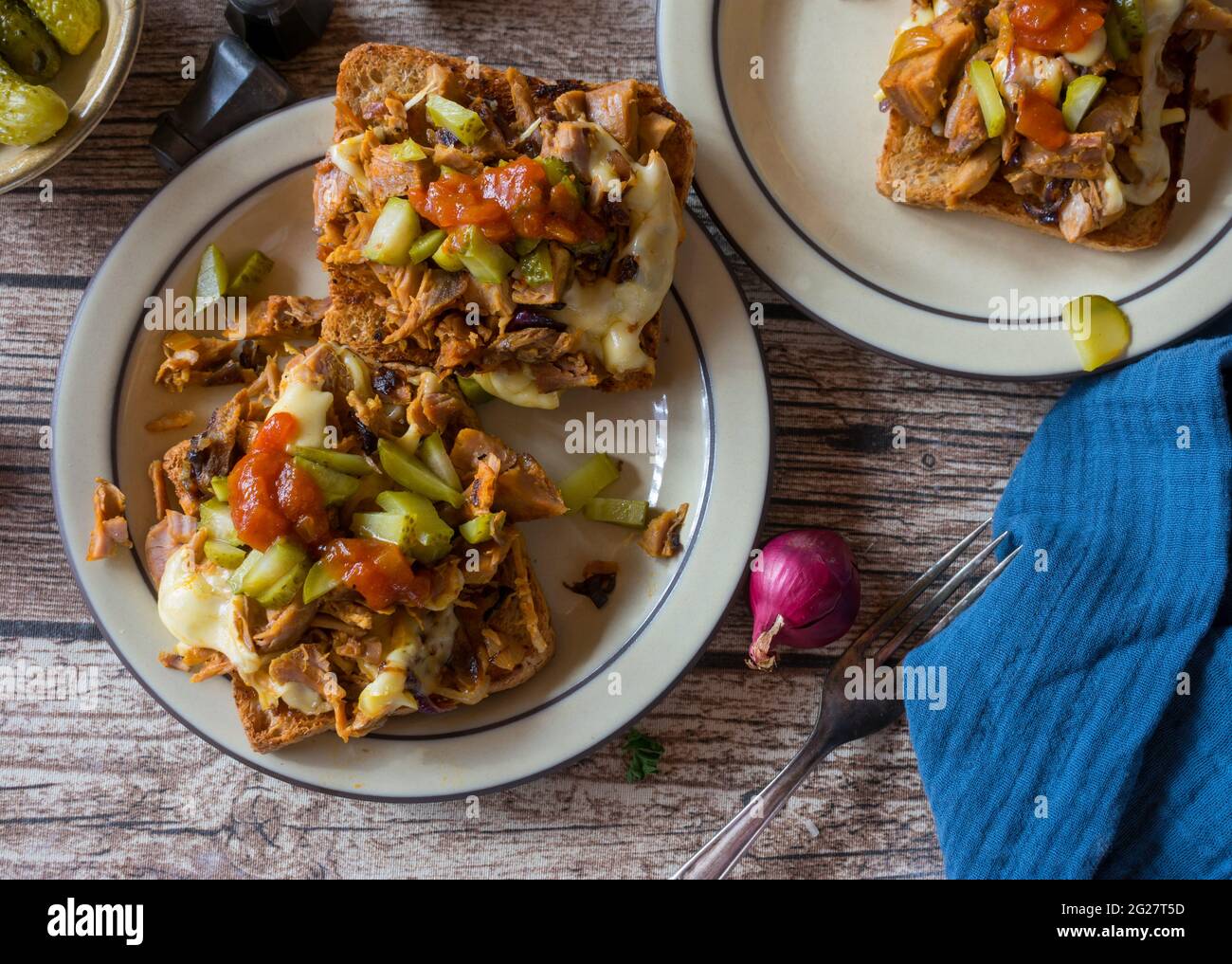 Gegrillter Toast mit Fleisch, Käse, Gurken, glasierten Zwiebeln und Barbecue-Sauce auf rustikalem und Holztisch Hintergrund. Draufsicht Stockfoto