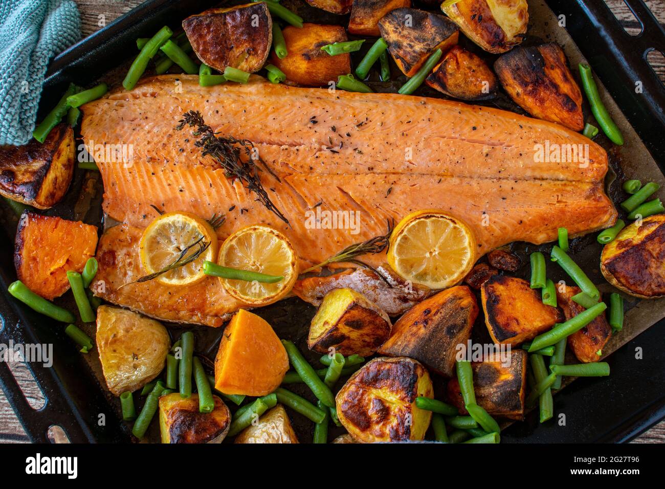 Mediterranes Fischgericht mit Gemüse und Süßkartoffeln auf einem Backblech von oben serviert. Nahaufnahme und abgelegene Sicht. Stockfoto
