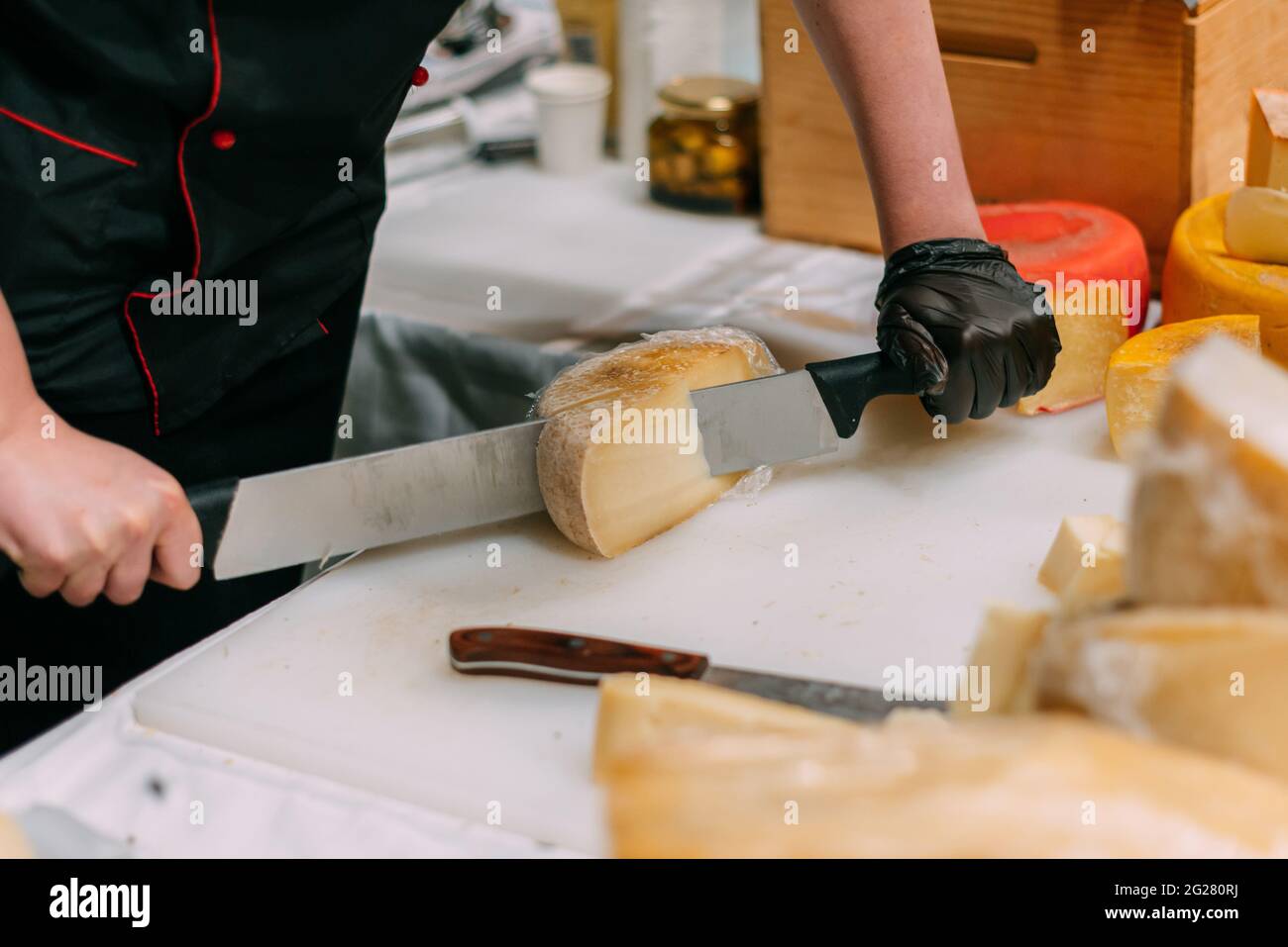 Handwerker schneidet handgemachten Käse in einem Geschäft. Stockfoto