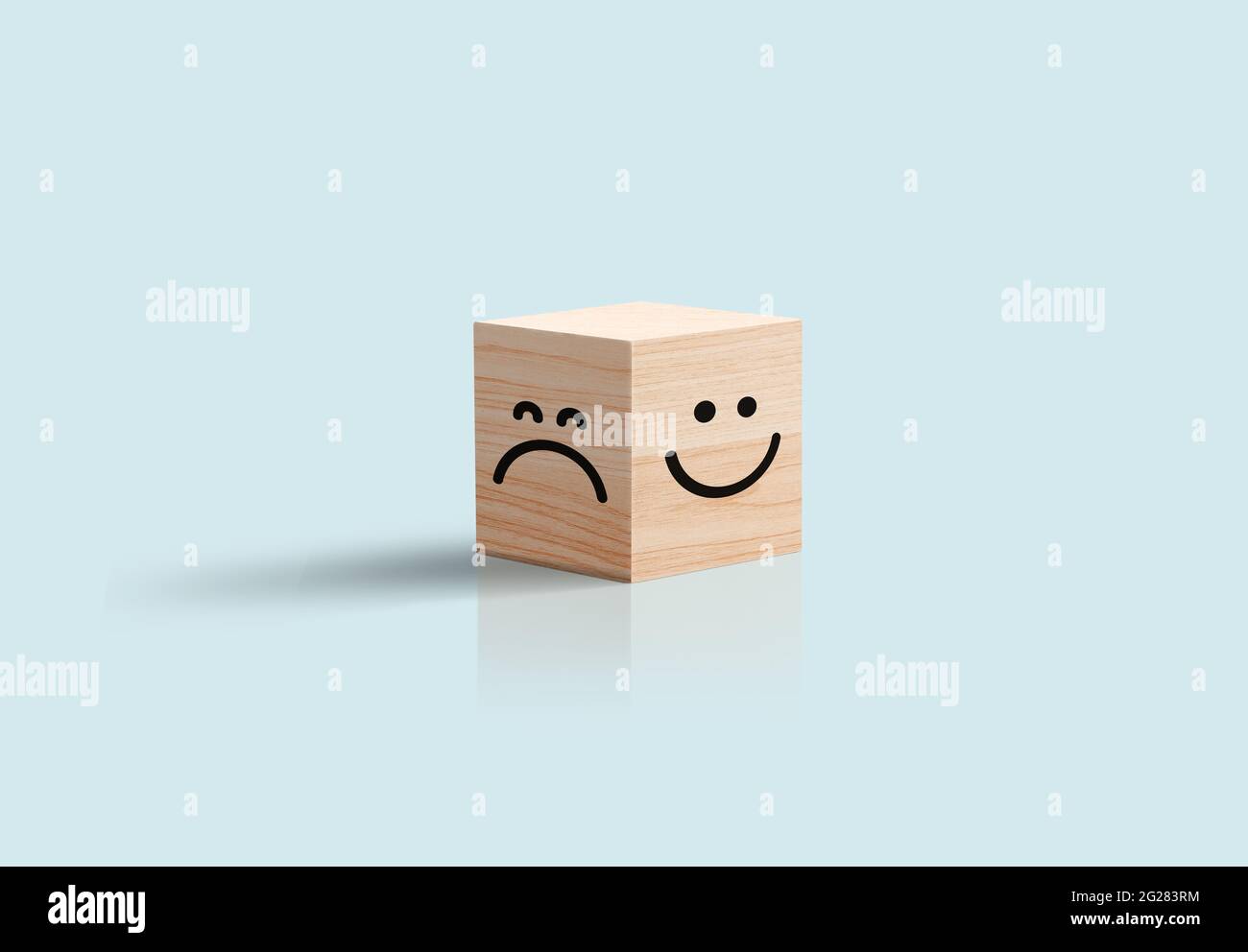 Glückliches und trauriges Gesicht in Wooden Cube Business Concept. Blauer Hintergrund. Positives negatives Feedback, Kundenbewertung, optimistischer Pessimist-Charakter Stockfoto