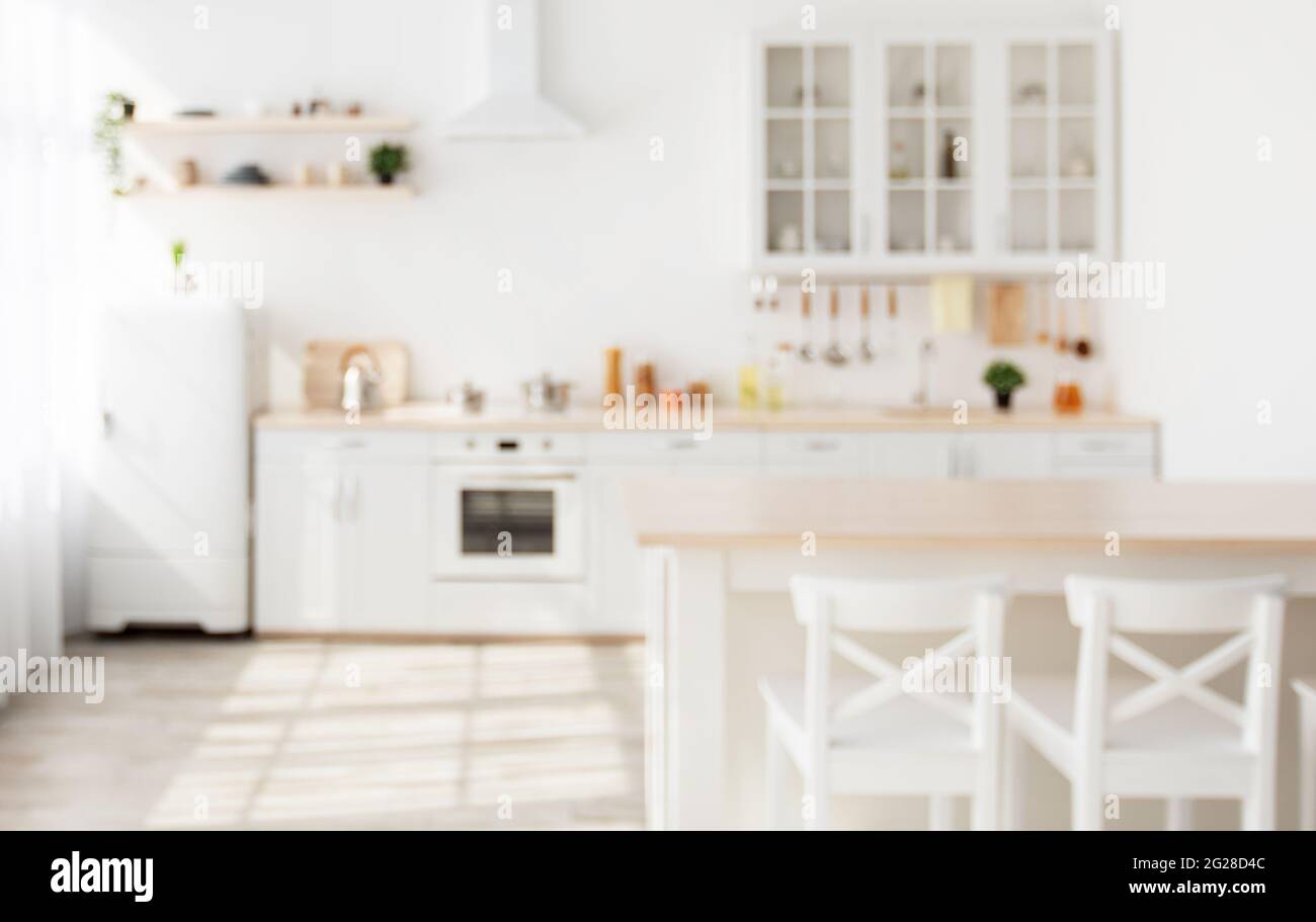 Verschwommener Hintergrund mit Familien-Esszimmer und minimalistischer Kücheneinrichtung, Küchenutensilien und Utensilien auf Möbeln Stockfoto