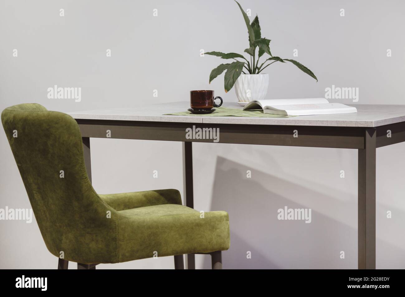 Moderner minimalistischer Arbeitsplatz. Sessel aus grünem Velours und Loft-Tisch mit Heimpflanze in weißem Topf Stockfoto