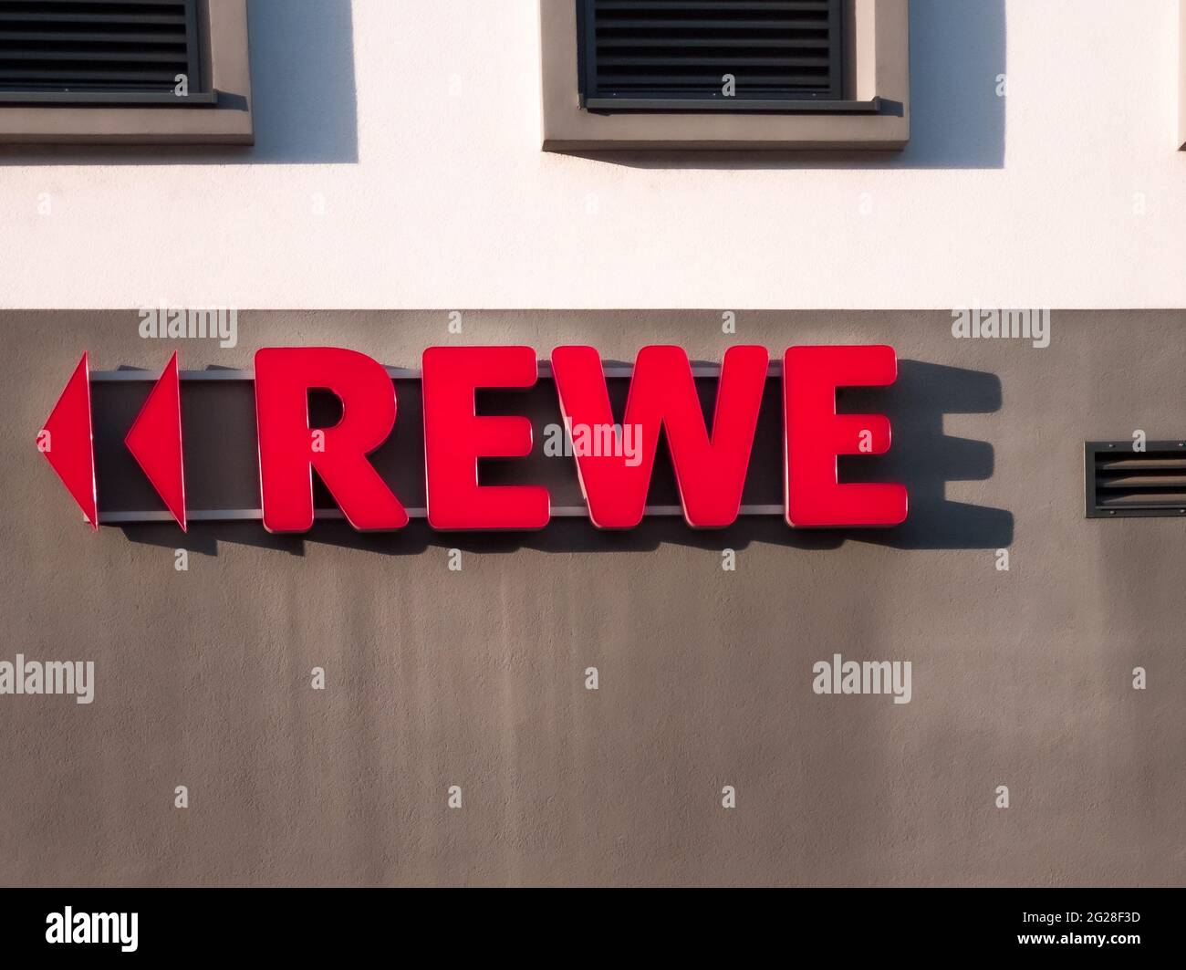 NEUWIED, DEUTSCHLAND - 12. Nov 2020: Neuwied, Deutschland - 12. November 2020: Rotes REWE Label mit Dreiecken als Richtungszeichen außen an einer Wand - copy Spa Stockfoto