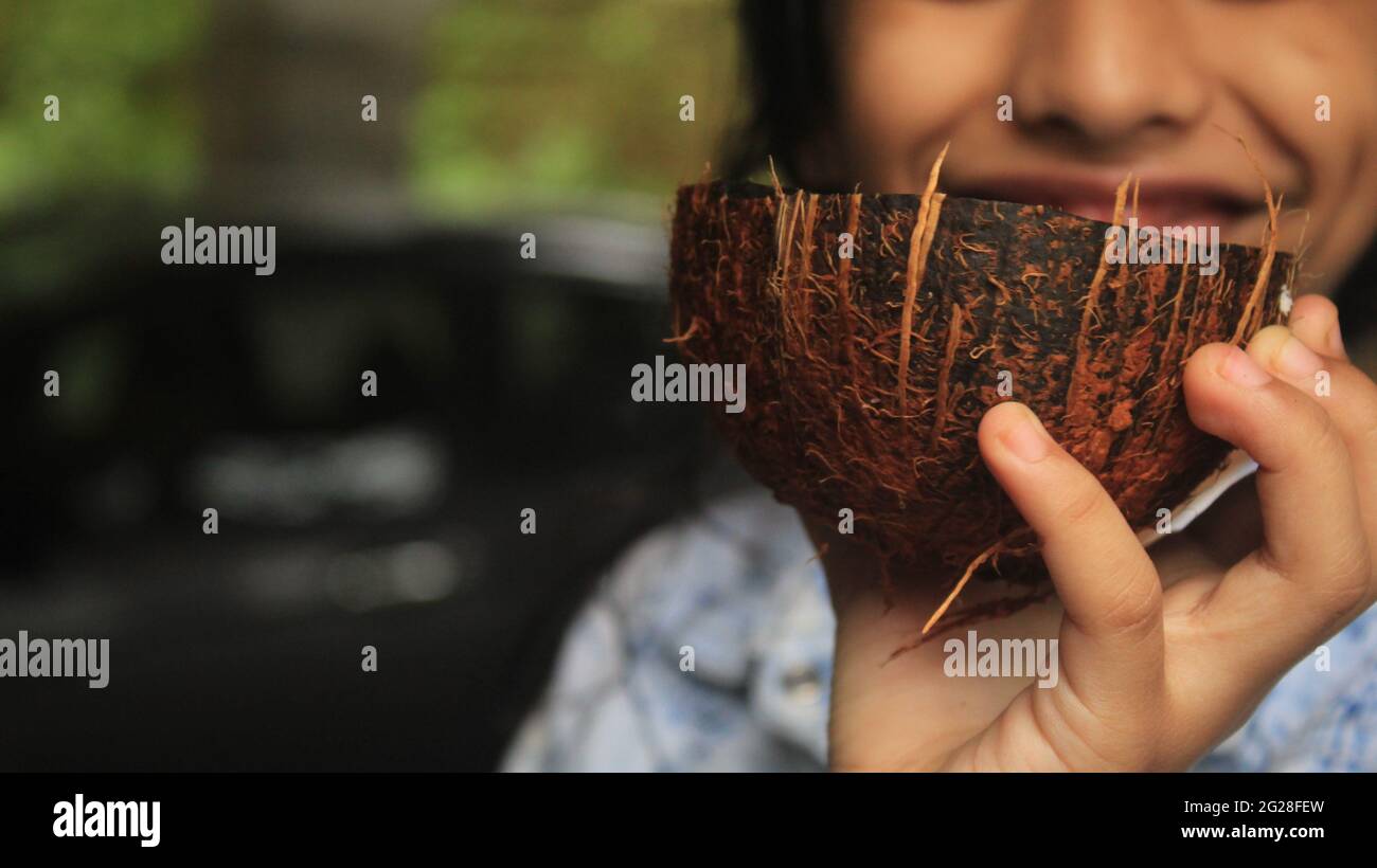Mädchen hält einen Kokosnuss-Husk mit wachsenden Erdnüssen darin. Stockfoto