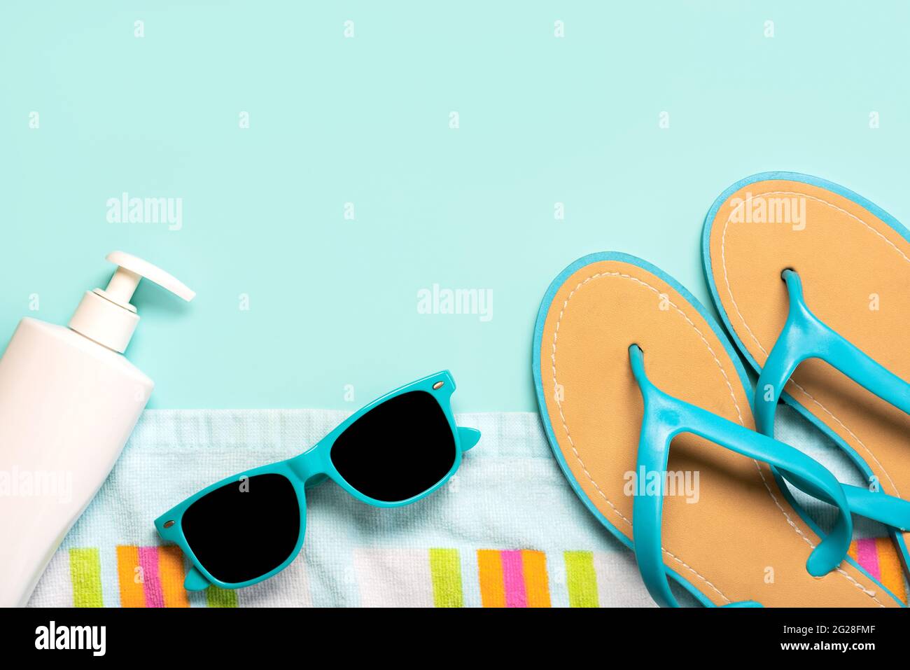 Sommerferienkonzept.Draufsicht auf blaue Flip Flops, Strandtuch, blaue Sonnenbrille und eine Flasche Sonnencreme mit Kopierfläche auf blauem Hintergrund Stockfoto