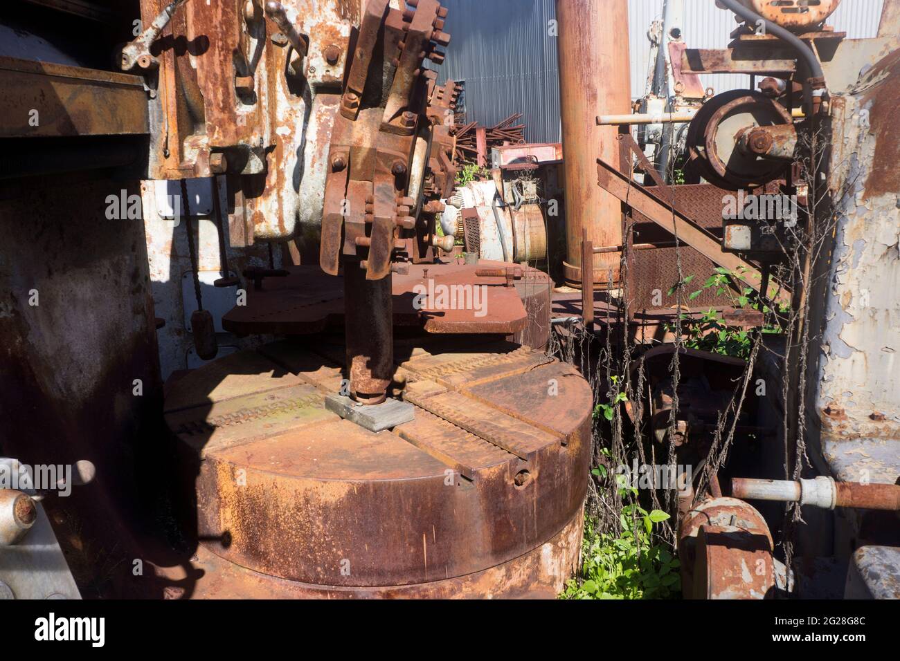 Alte veraltete Industriemaschinen sitzen und rosten in einem Schrottplatz im Land. Stockfoto