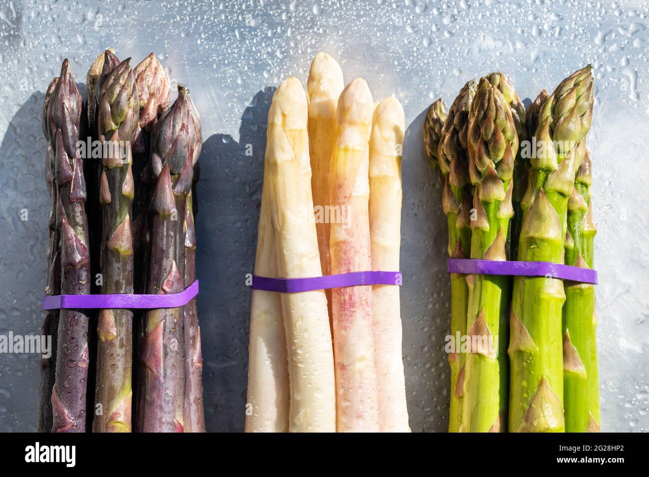 Grüner, violetter und weißer Spargel sprießt auf Metallbrett. Draufsicht flach liegend. Food-Fotografie Stockfoto