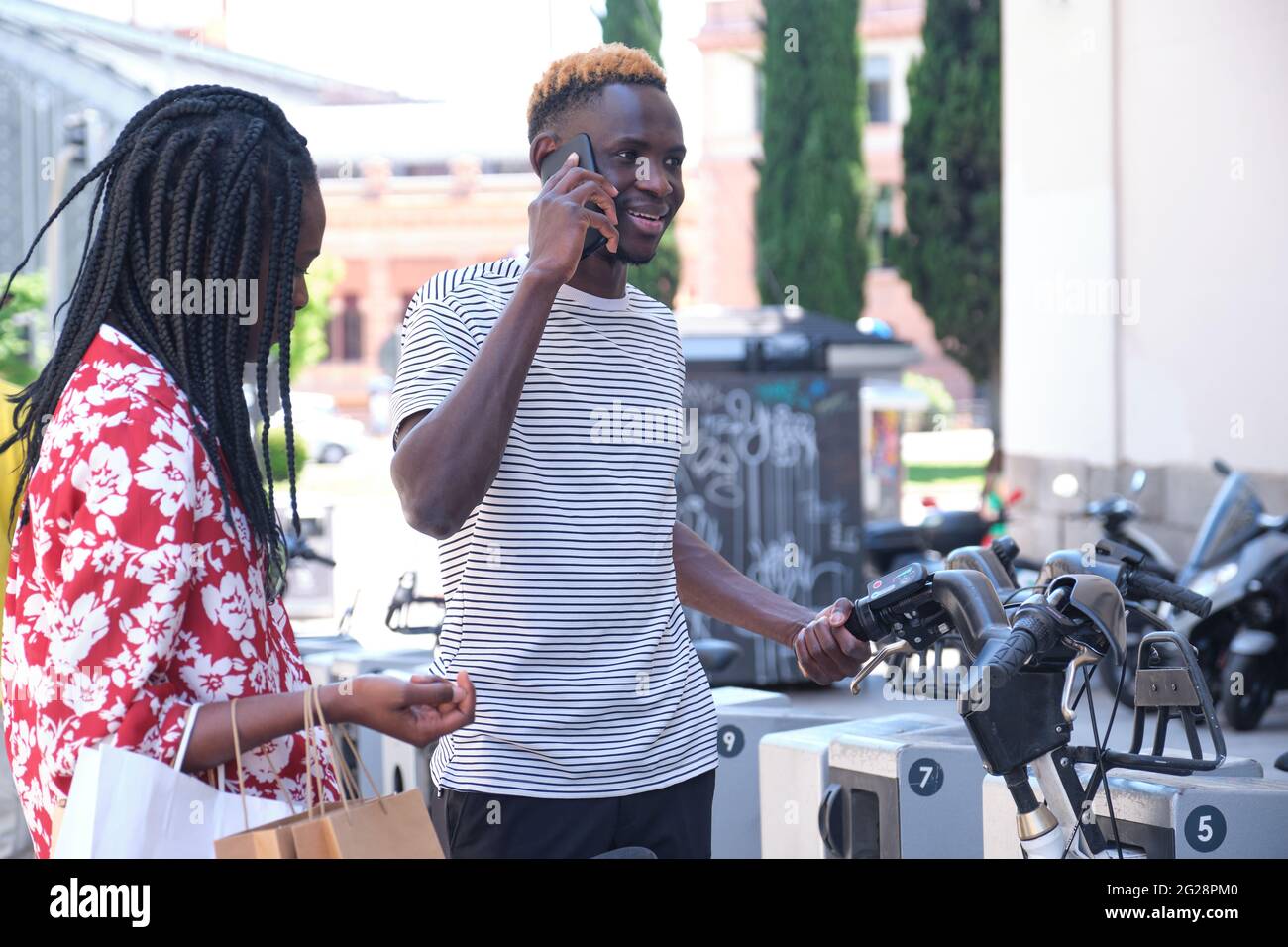 Junge afrikanische Touristen mieten ein Fahrrad an einem Fahrradverleih Service-Maschine. Stadtleben Konzept. Stockfoto