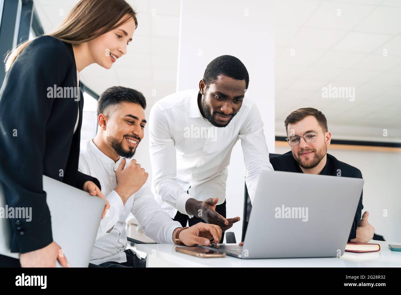 Gruppe von mehrrassischen Angestellten im Büro hinter einem Laptop Stockfoto